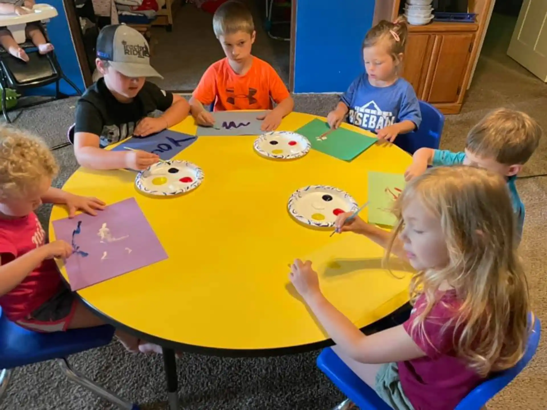 a group of children sitting around a table eating food