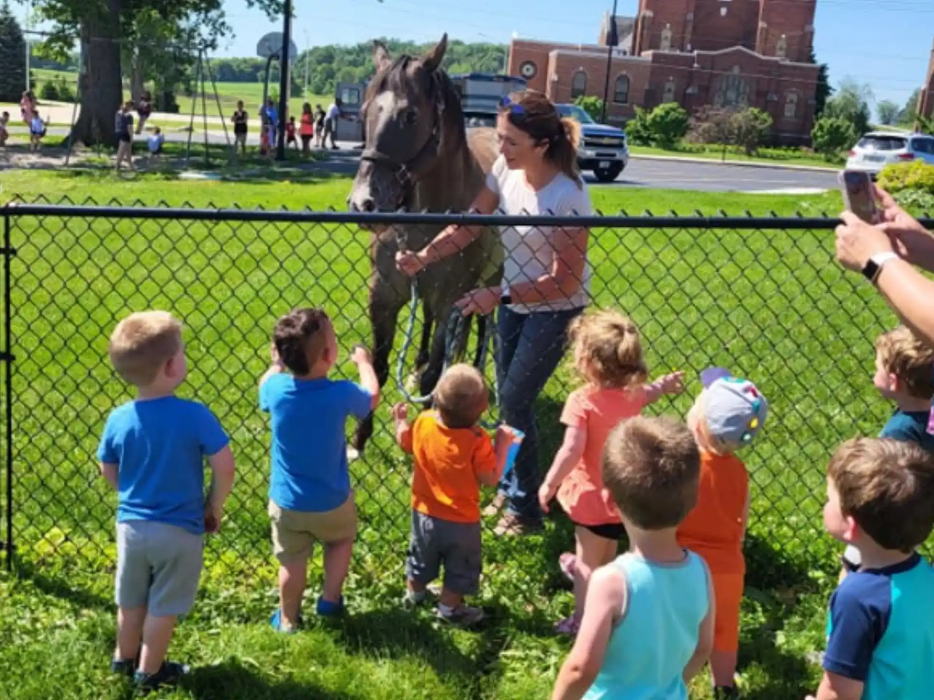 a group of children looking at a horse behind a fence