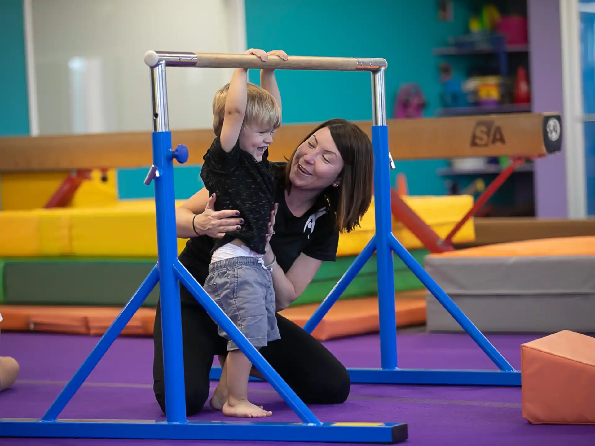 a woman holding a girl on a bar