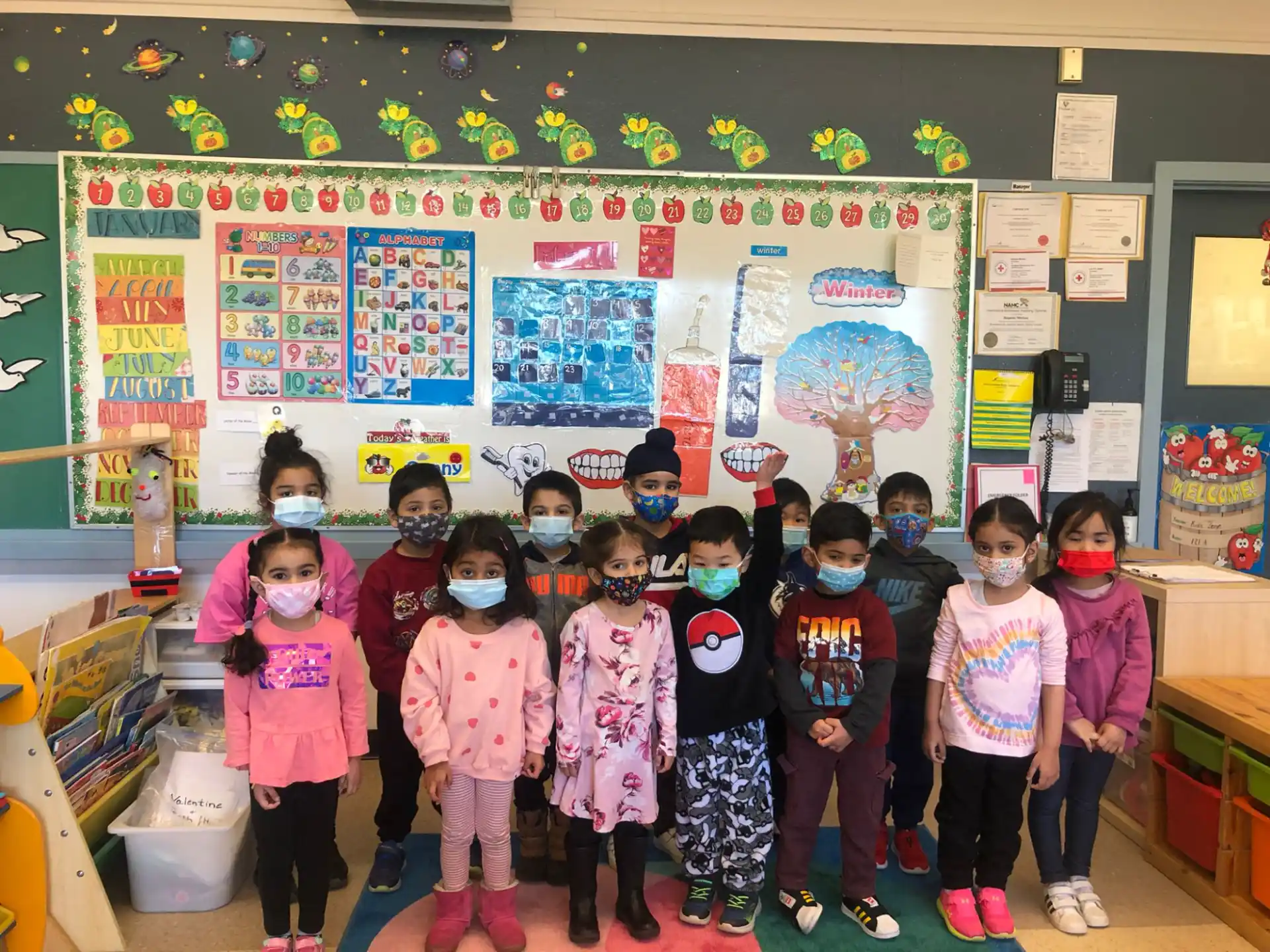 a group of children posing for a photo in front of a classroom