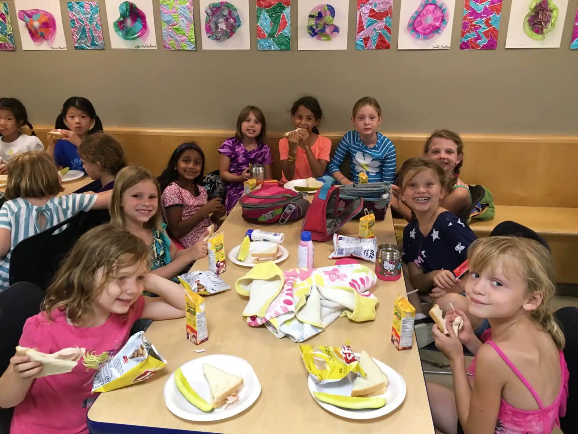 a group of children sitting at a table eating food