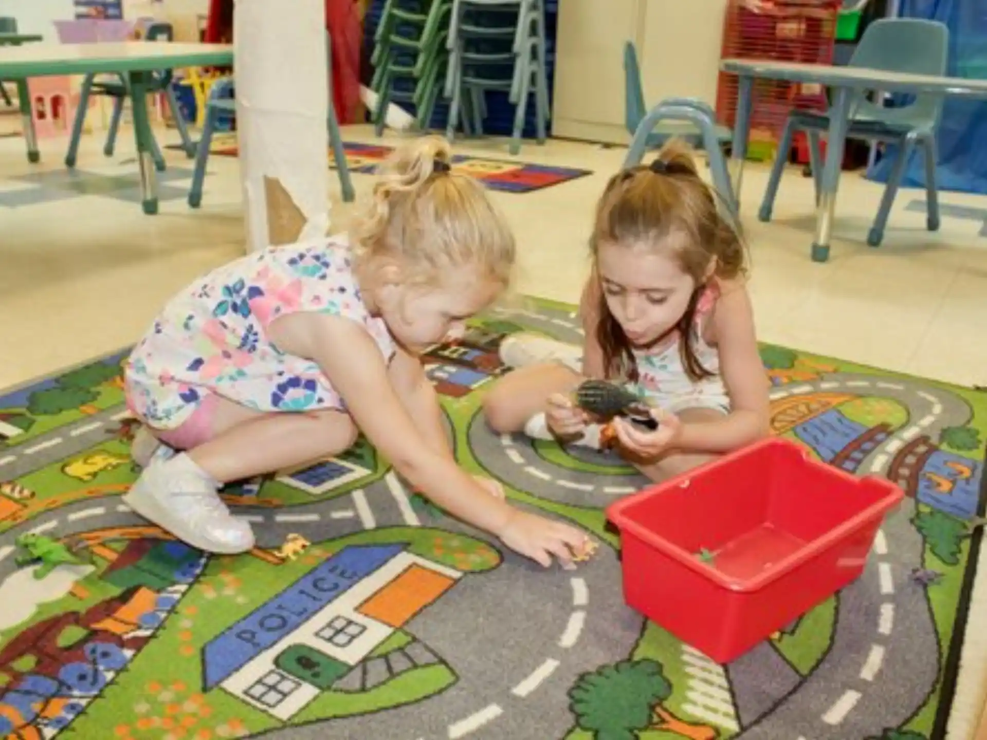 a couple of young girls playing with a toy on the floor