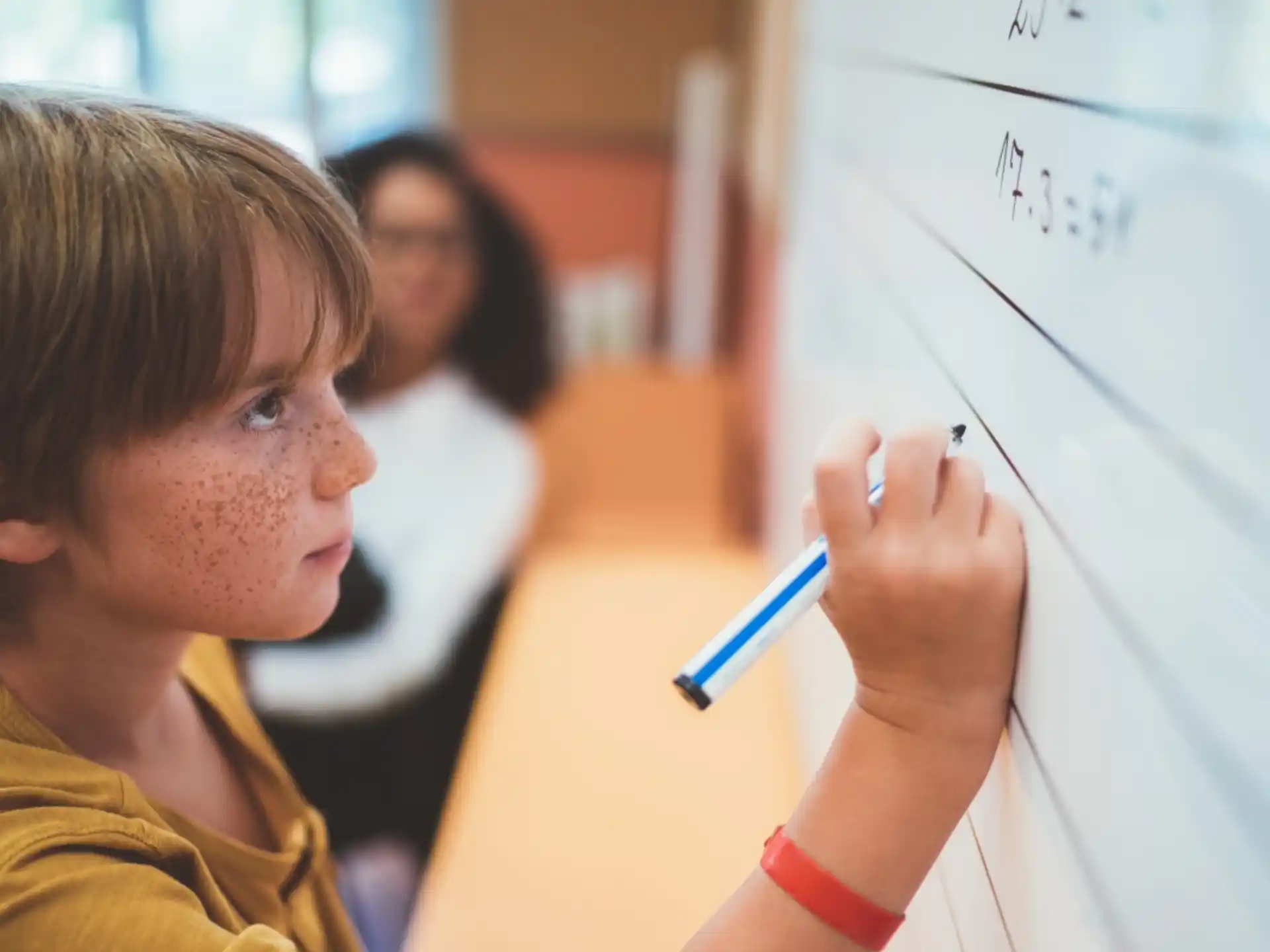 a young boy writing on a whiteboard