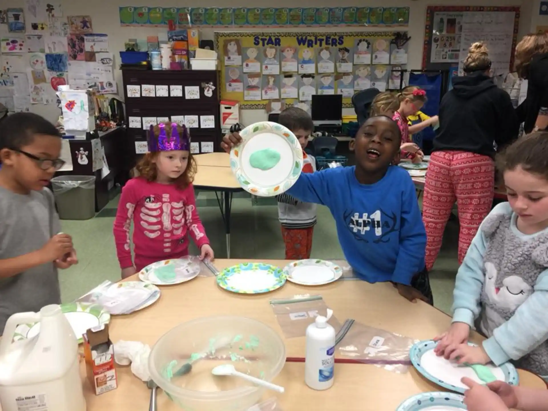a group of children sitting around a table with plates and cups