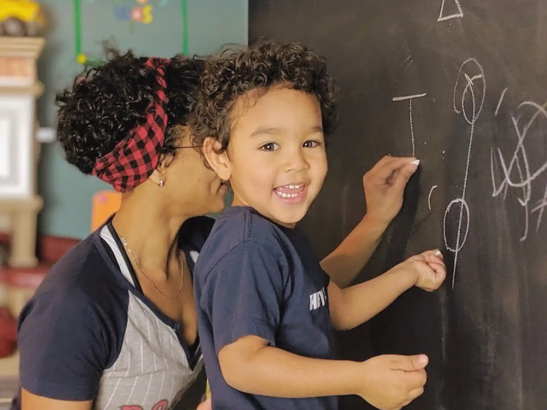 a young girl and a young boy writing on a blackboard