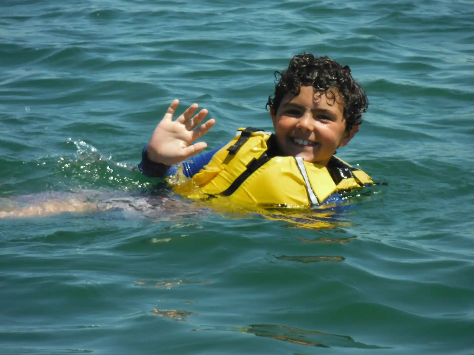a boy in a life jacket on a surfboard