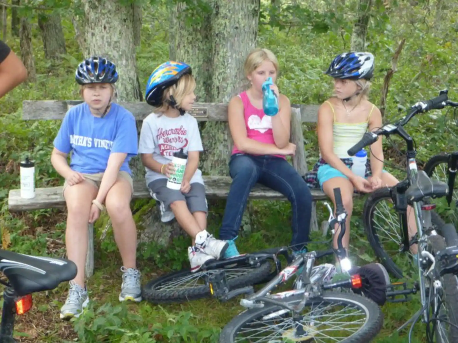 a group of people sitting on a bench with bicycles