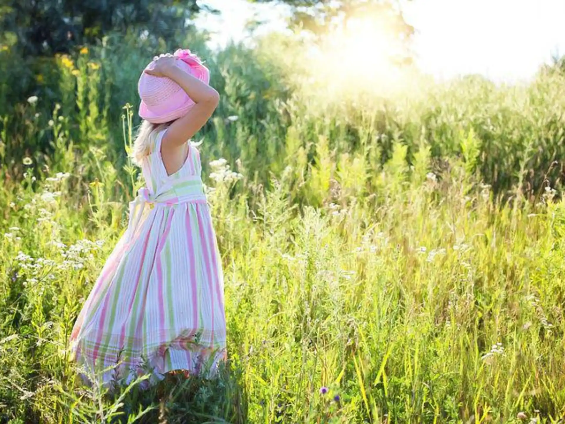 a girl in a dress standing in a field of tall grass