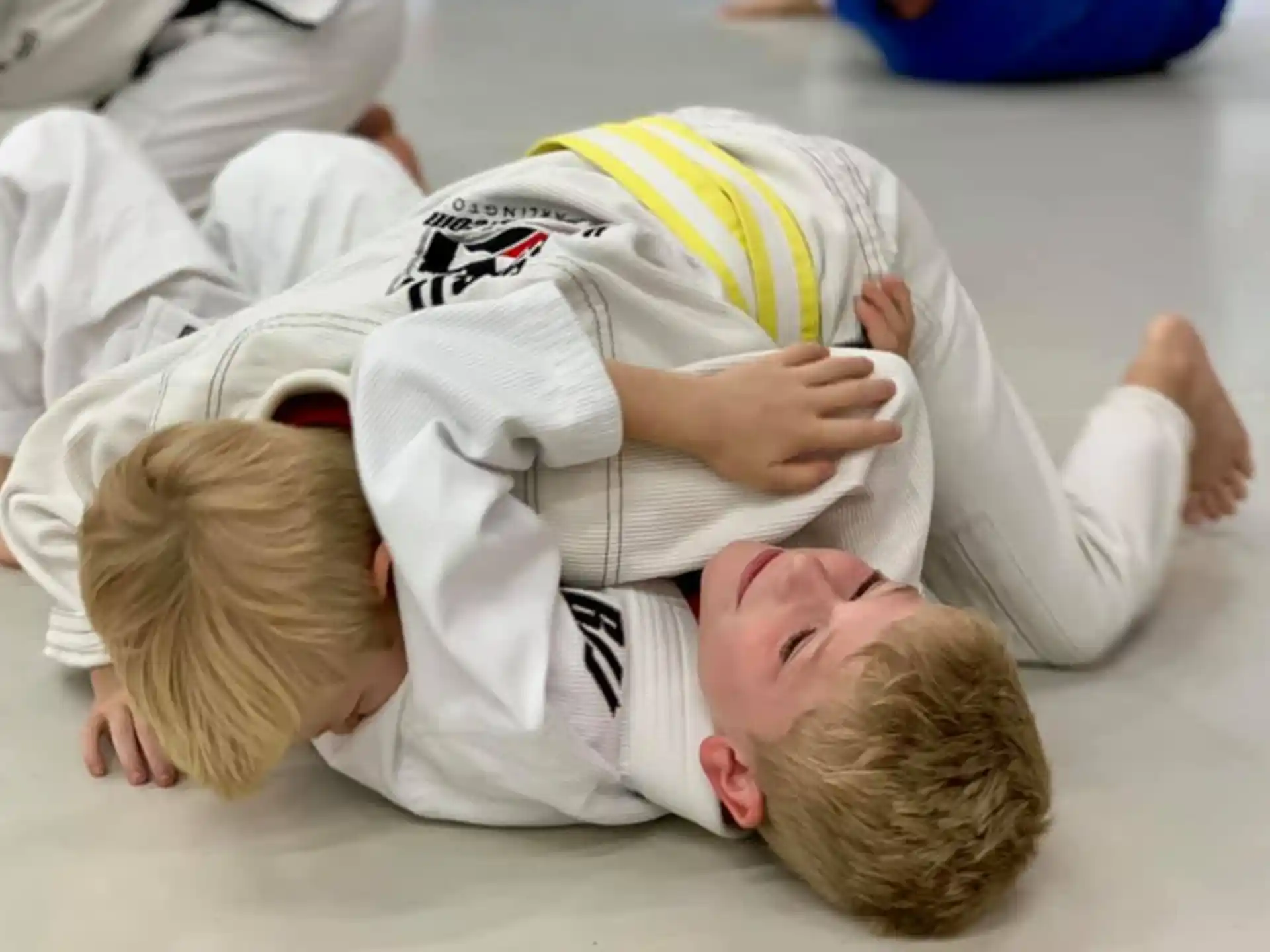 a boy lying on the ground with a baby on his back