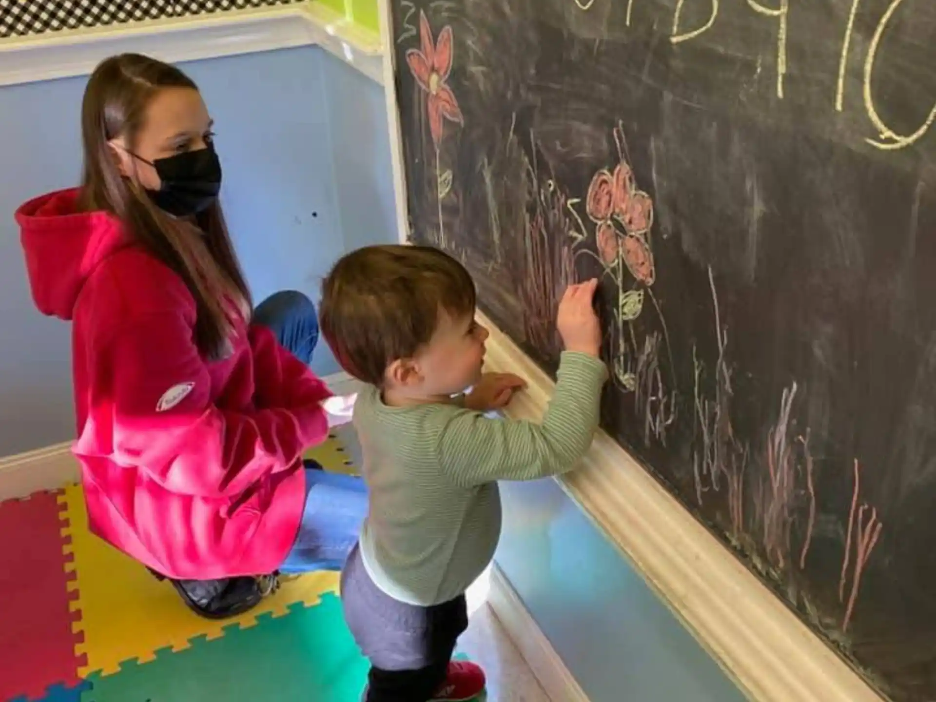 a person and a child writing on a chalkboard