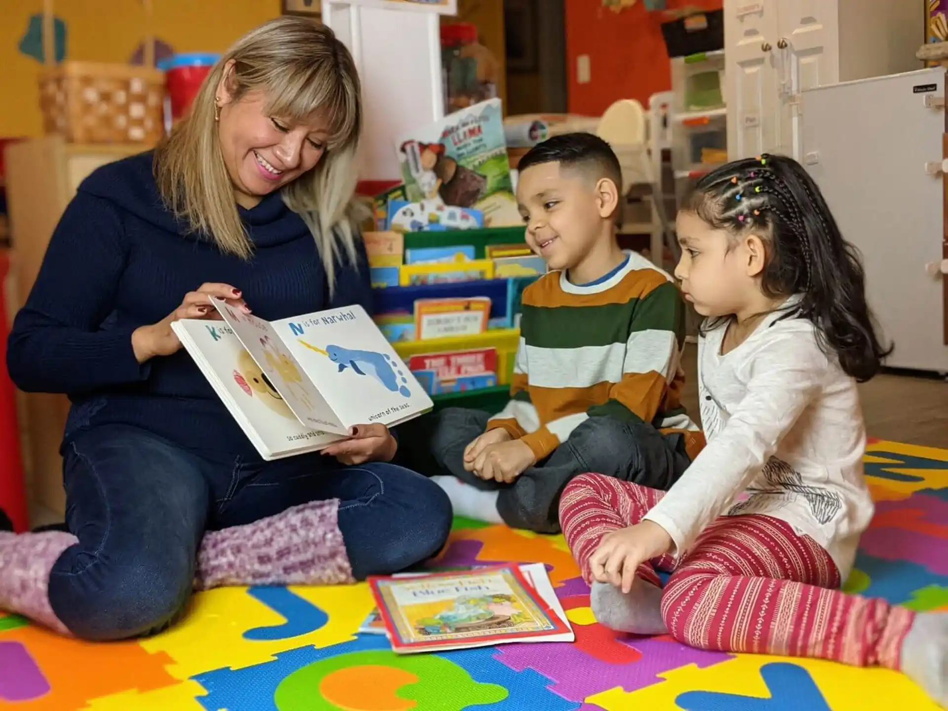 a woman and children sitting on the floor reading a book