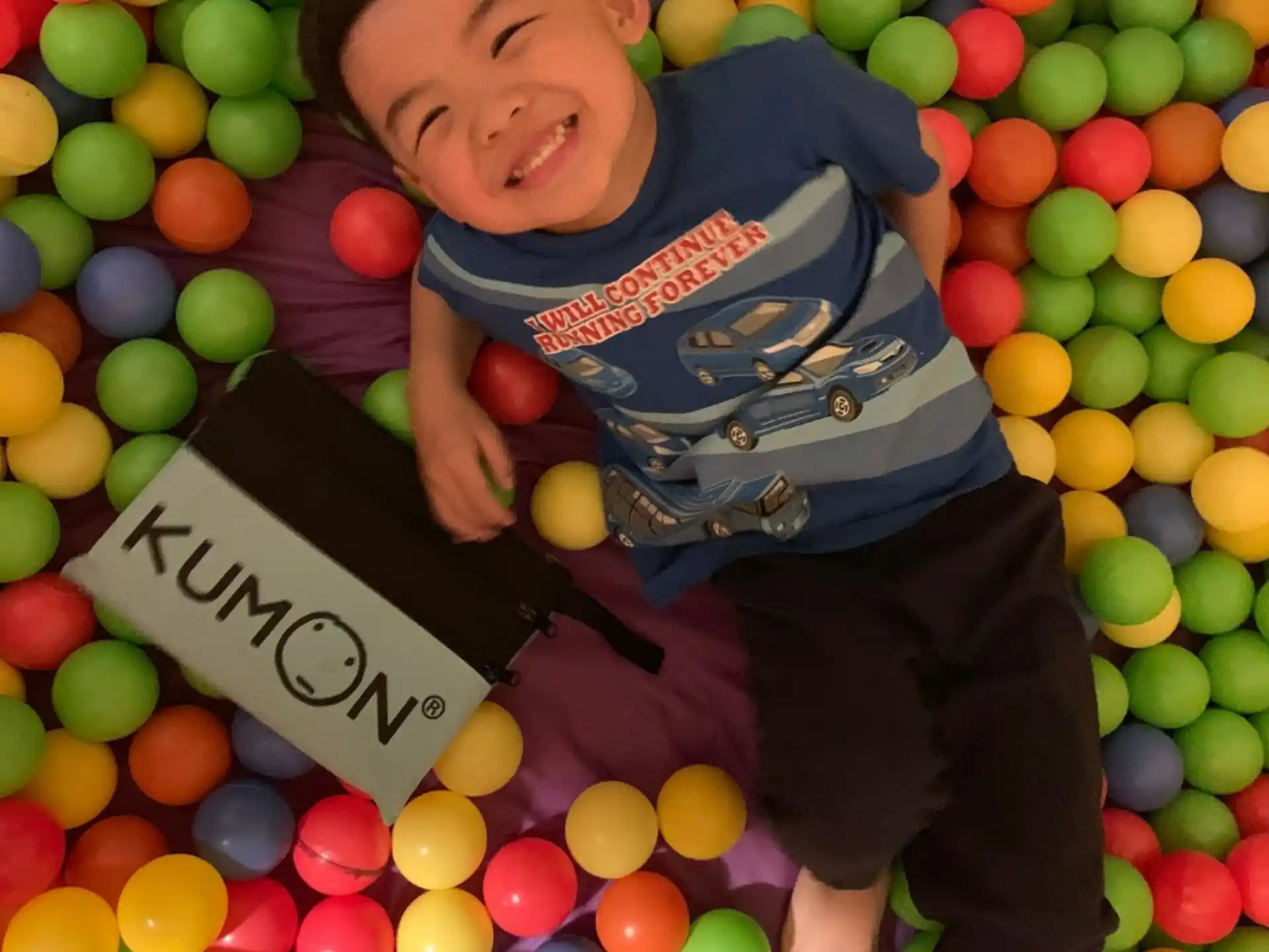 a boy lying on a ball pit