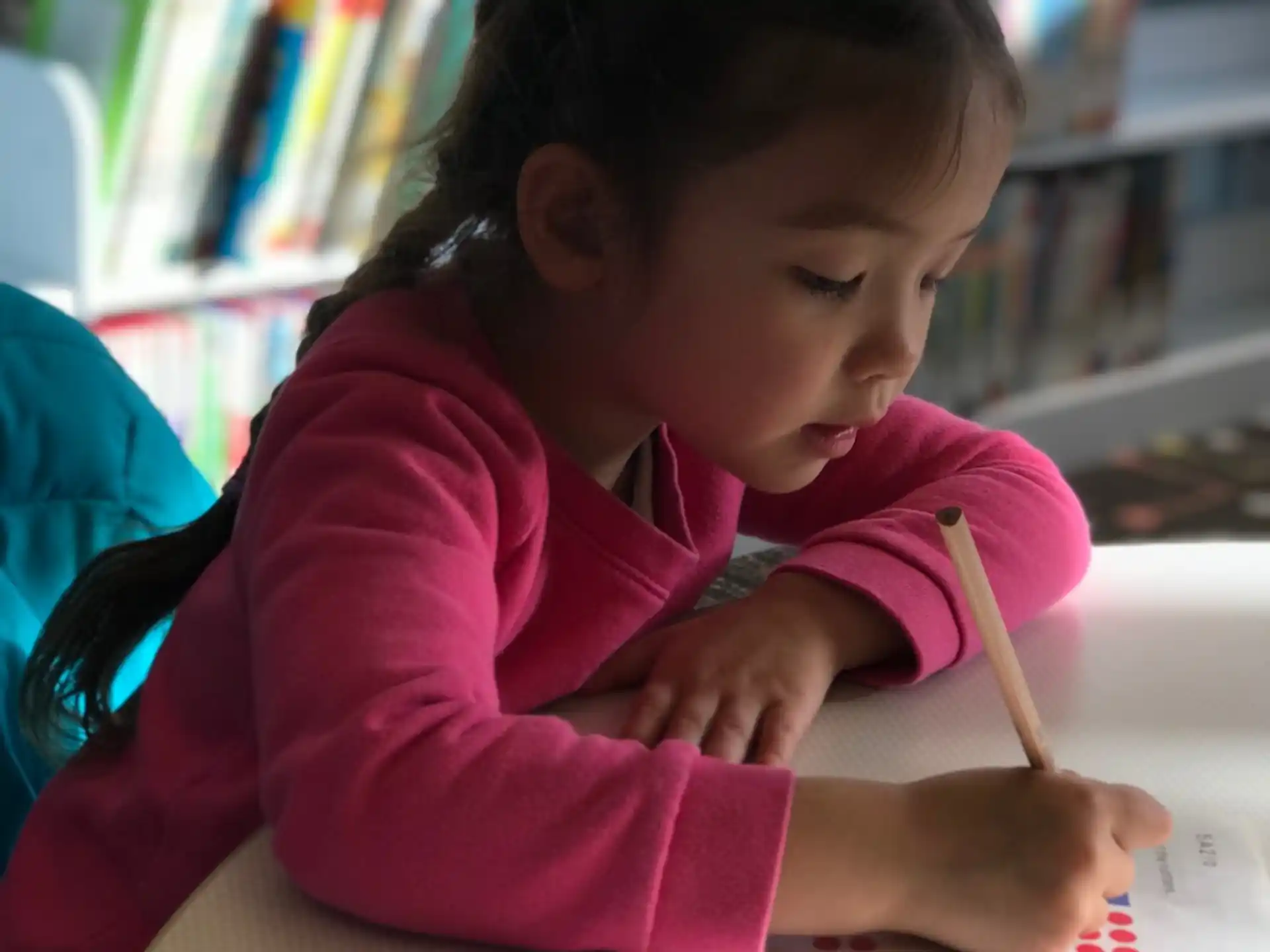 a young girl writing on a book