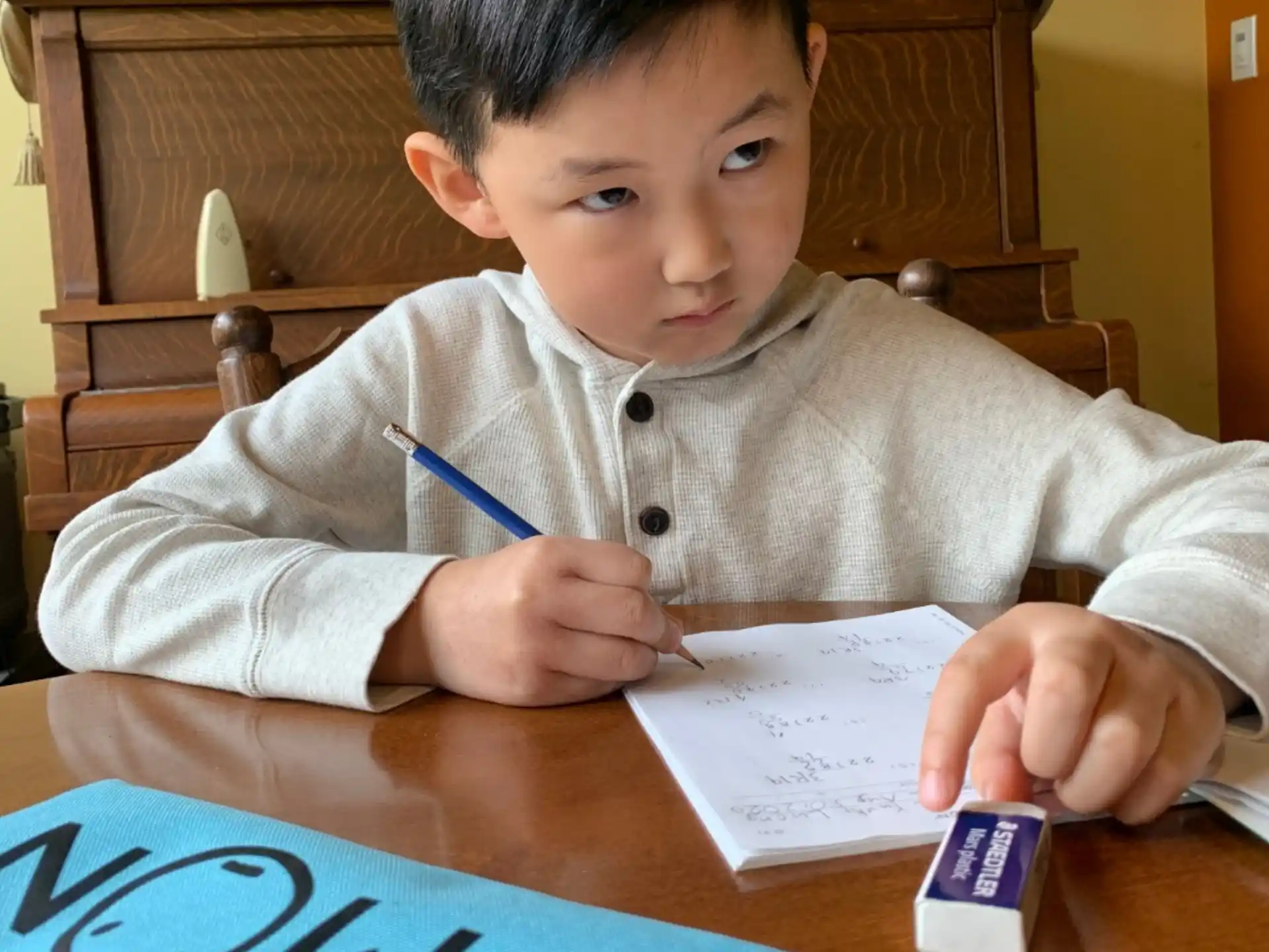 a boy sitting at a table writing on a piece of paper