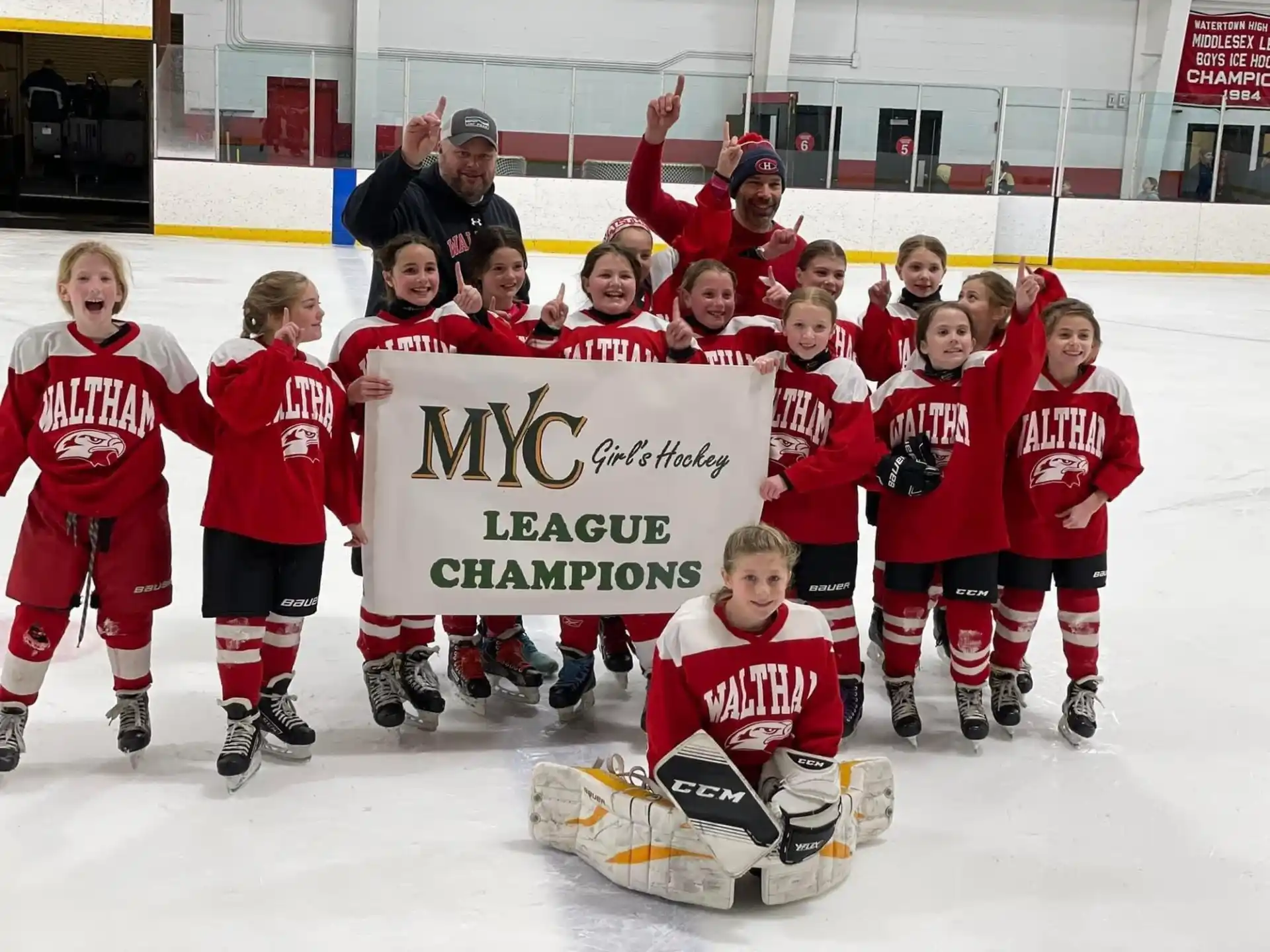 a group of people wearing hockey uniforms holding a sign