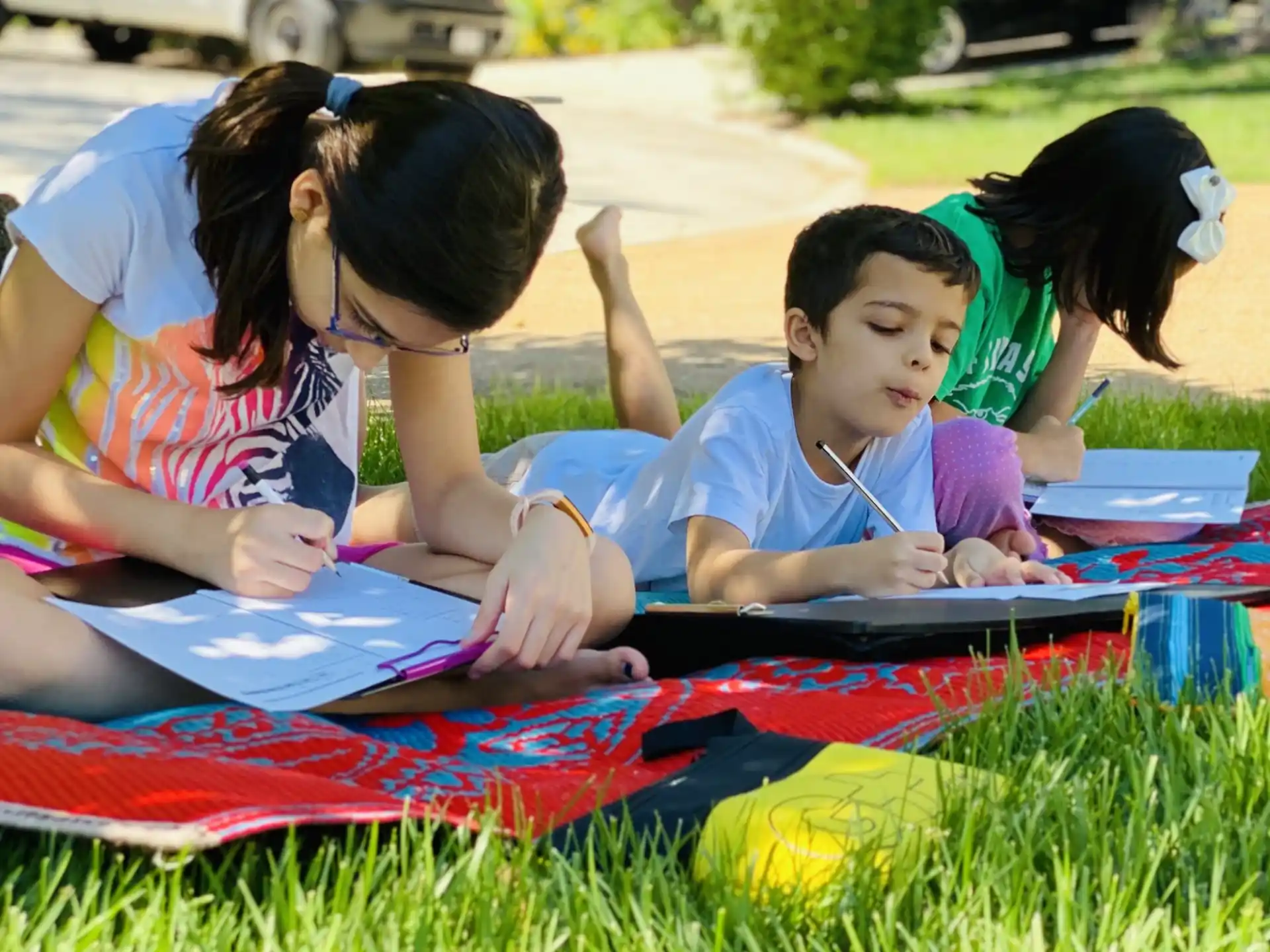 a person and two children sitting on a blanket in the grass