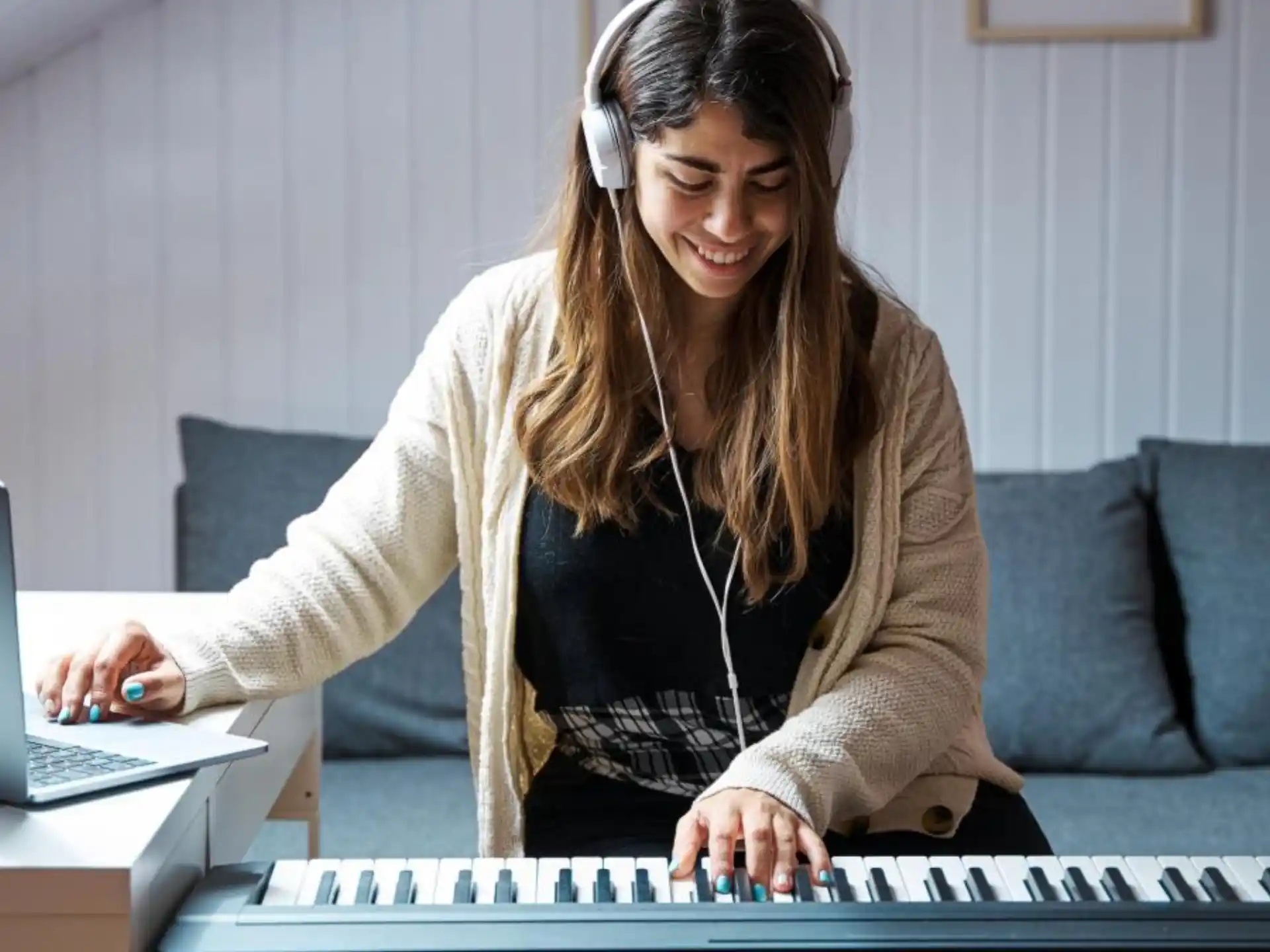 a person wearing headphones and sitting on a couch with a laptop