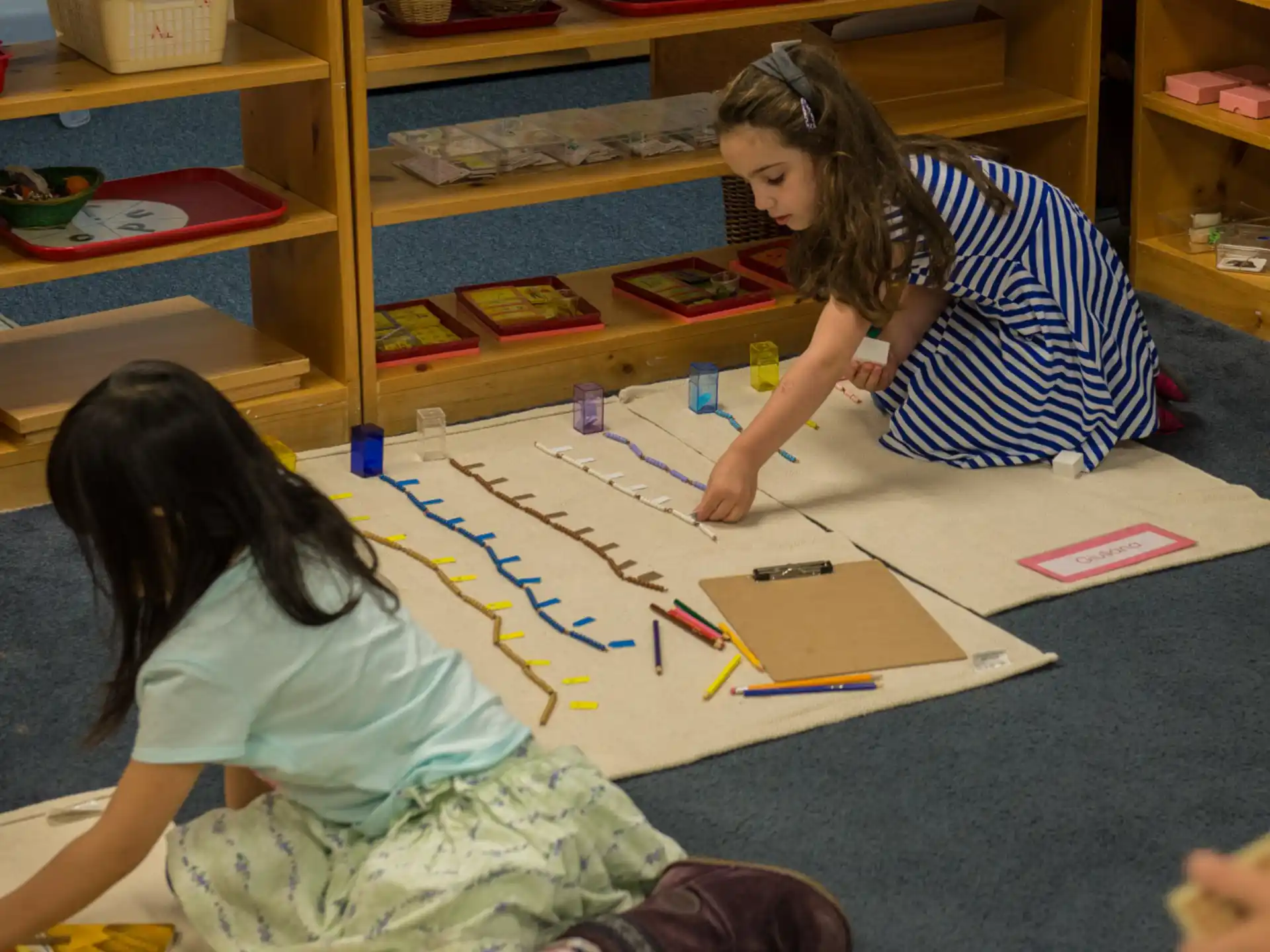 a couple of girls sitting at a table with colorful paper on it