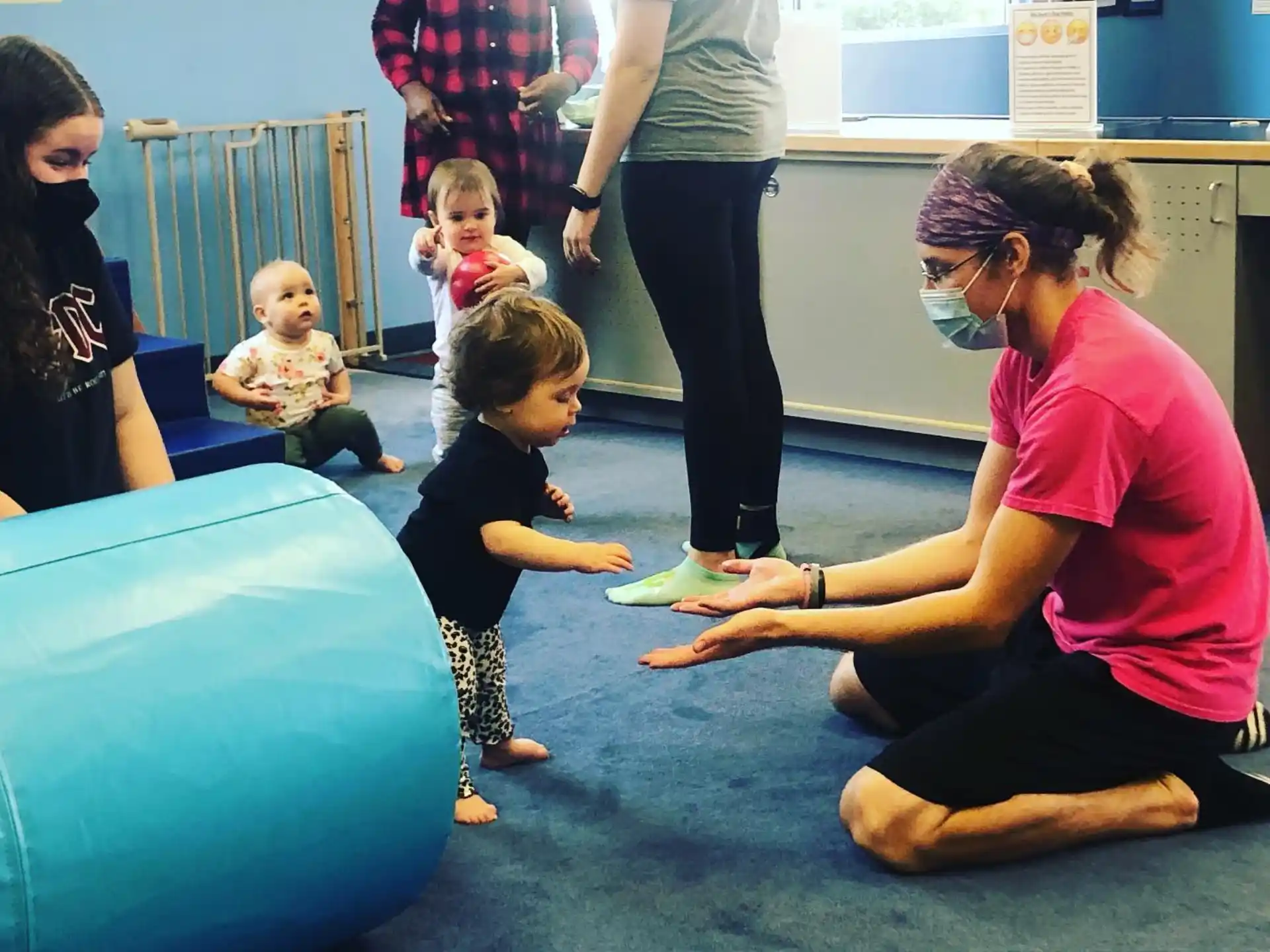 a person and a couple of children playing on a blue mat