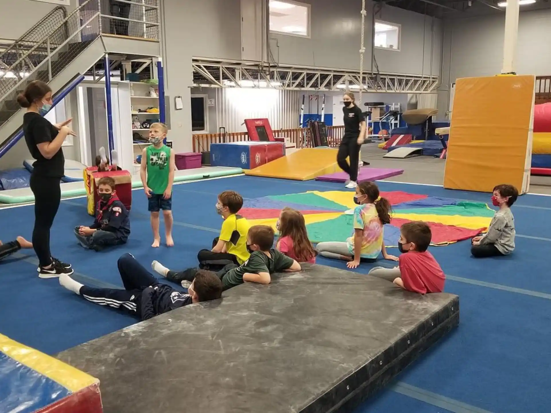 a group of children sitting on the floor in a gym