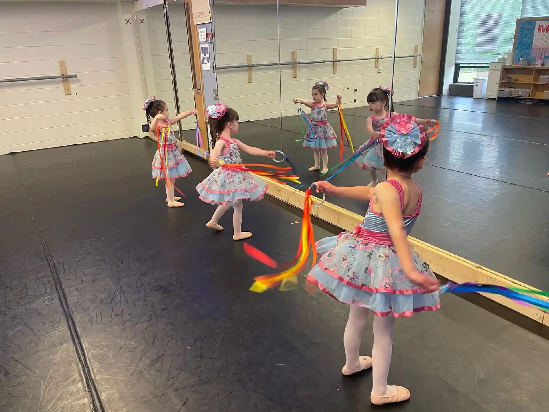 a group of girls in colorful dresses dancing in a room