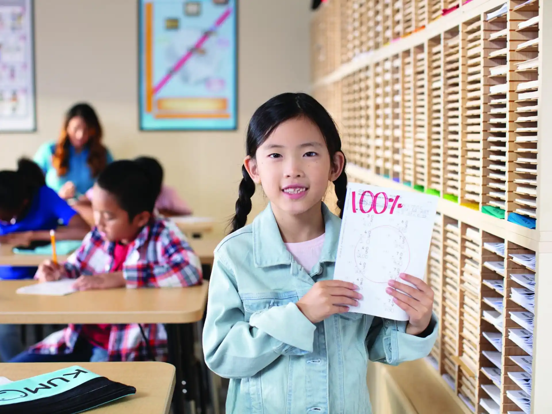 a young girl holding a piece of paper in a classroom