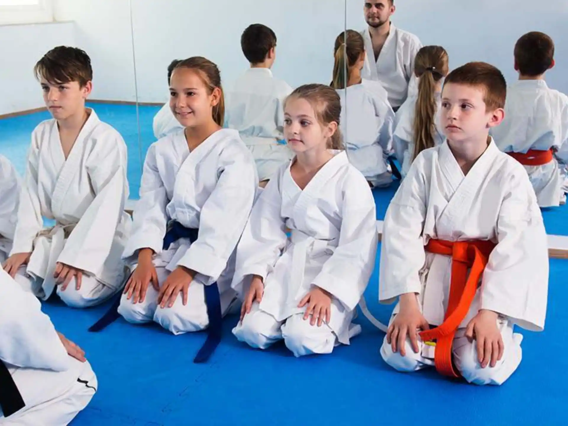 a group of people in white karate uniforms sitting on the floor