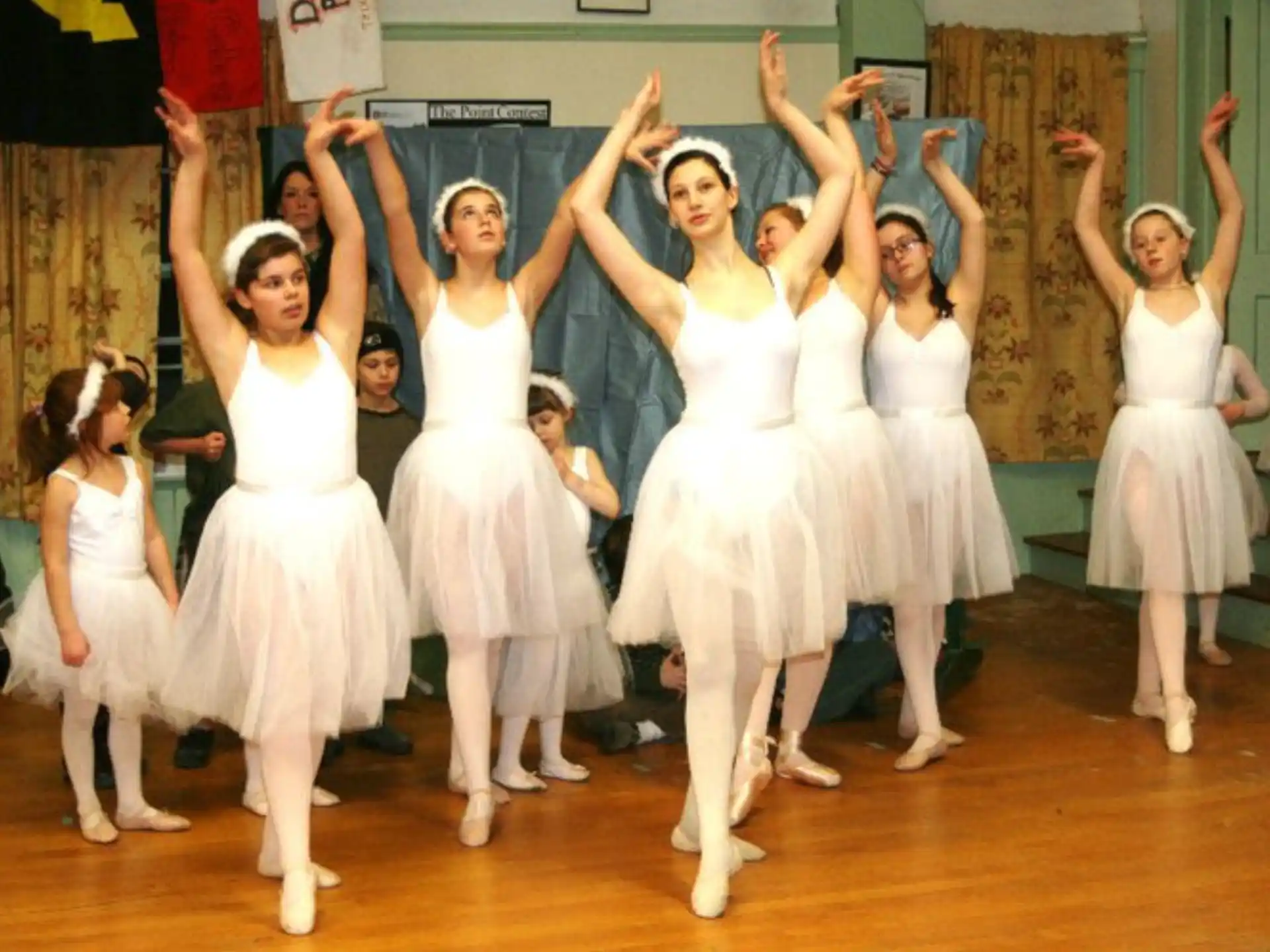 a group of girls in white dresses dancing on a stage