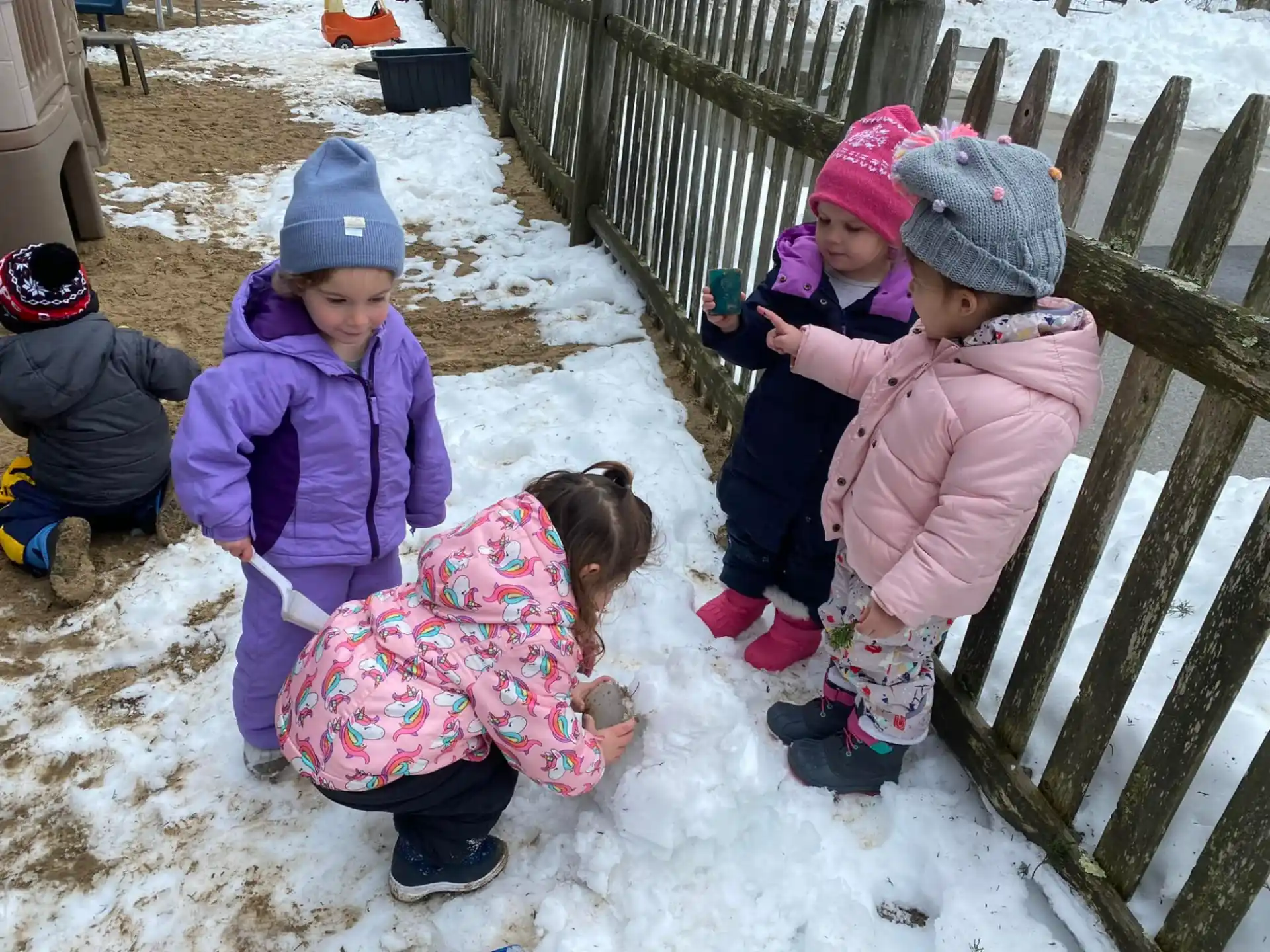 a group of children playing with a dog in the snow
