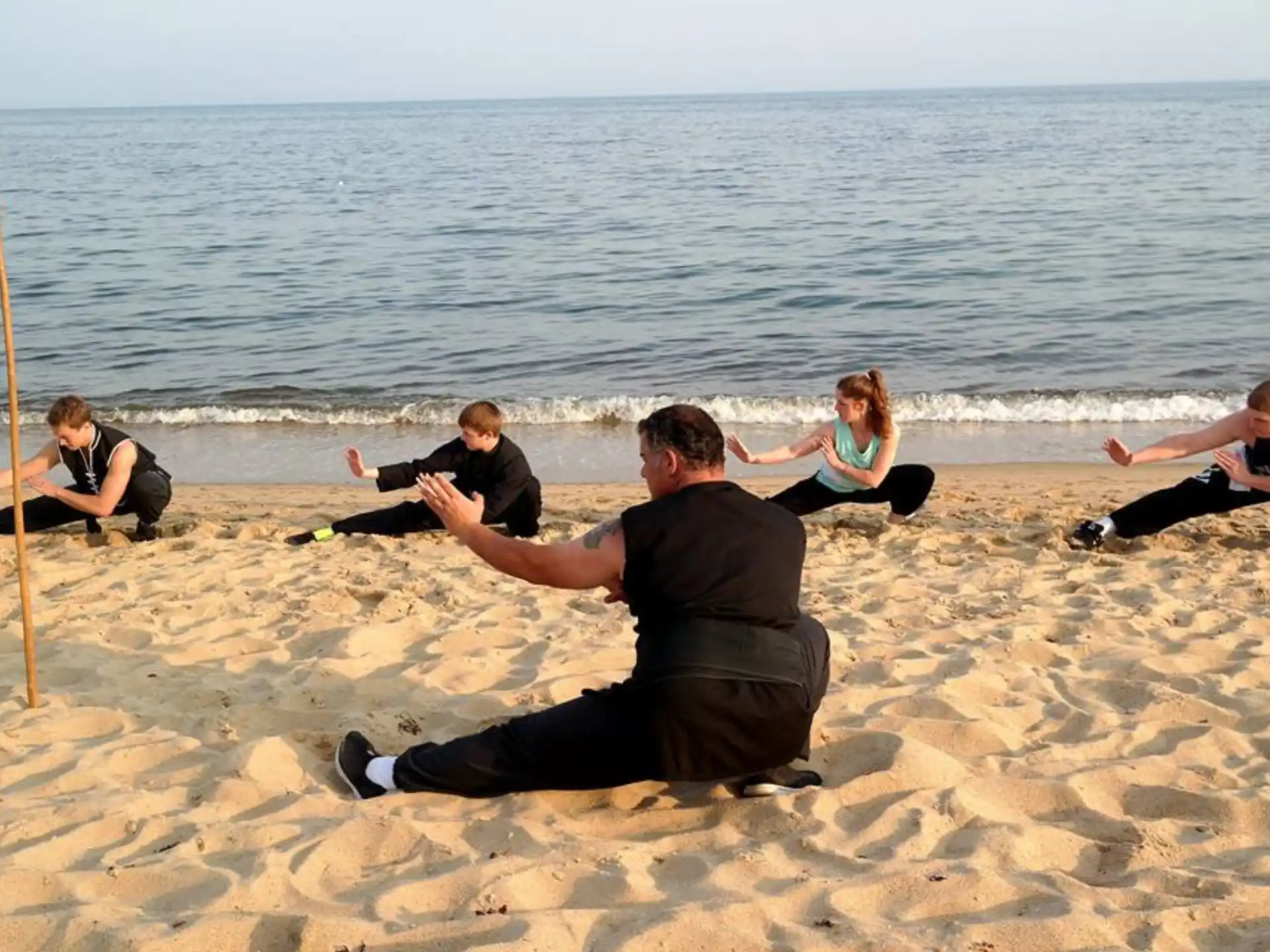 a group of people exercising on a beach