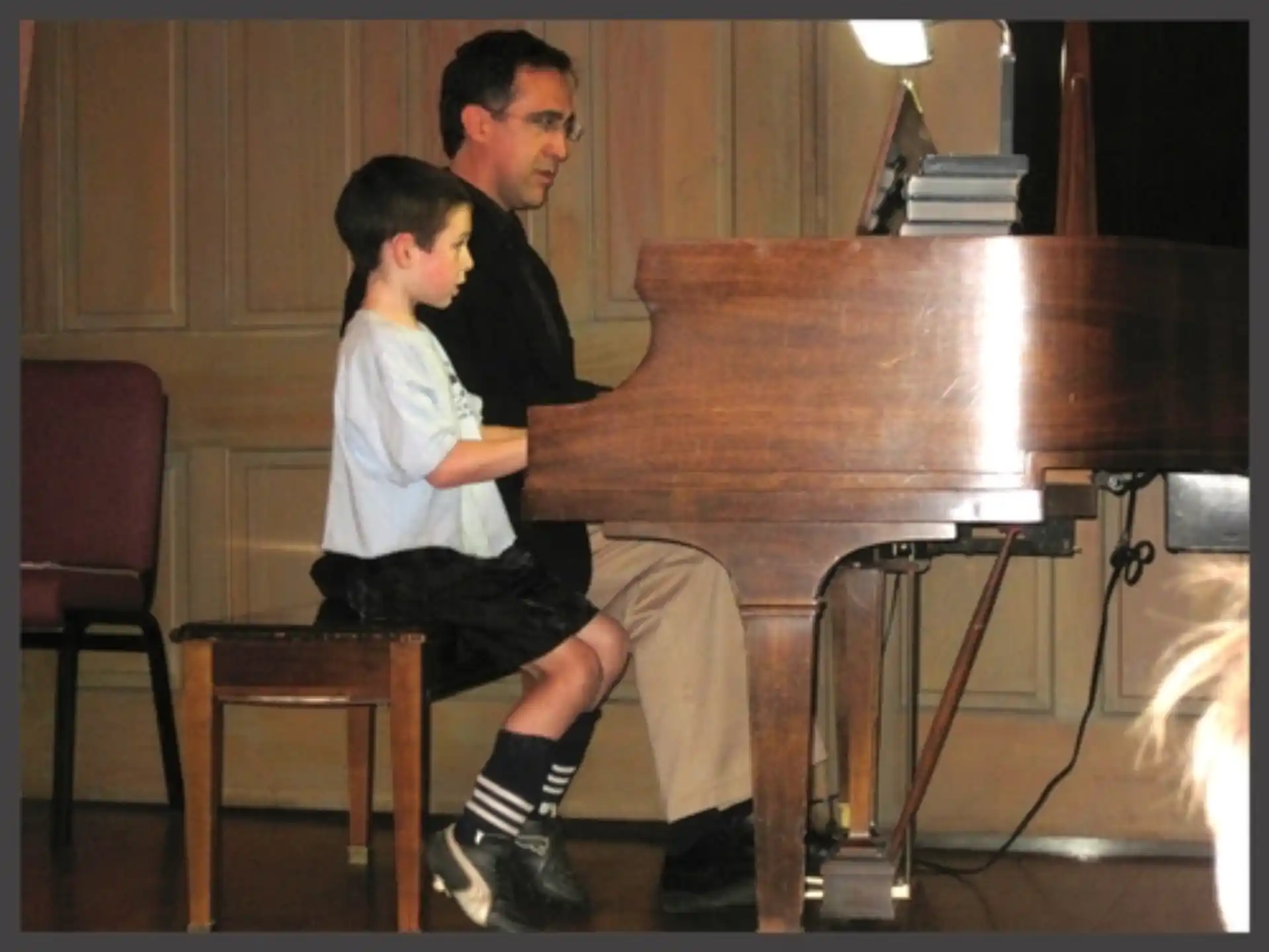 a man and a boy playing a piano