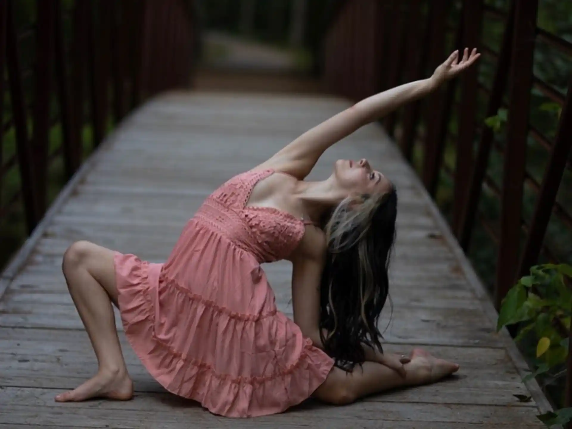 a person in a pink dress doing yoga on a wooden deck
