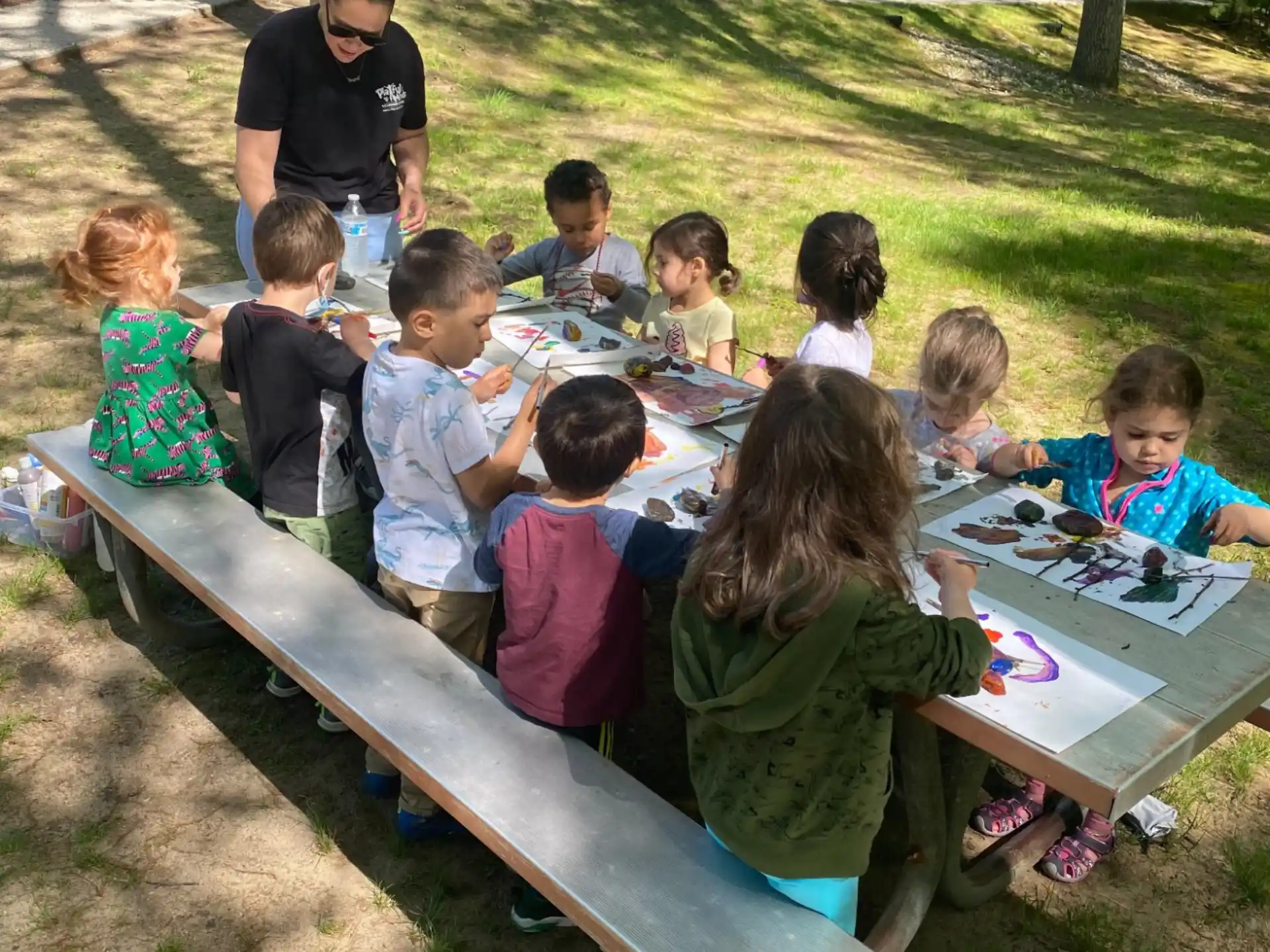 a group of children sitting at a table outside