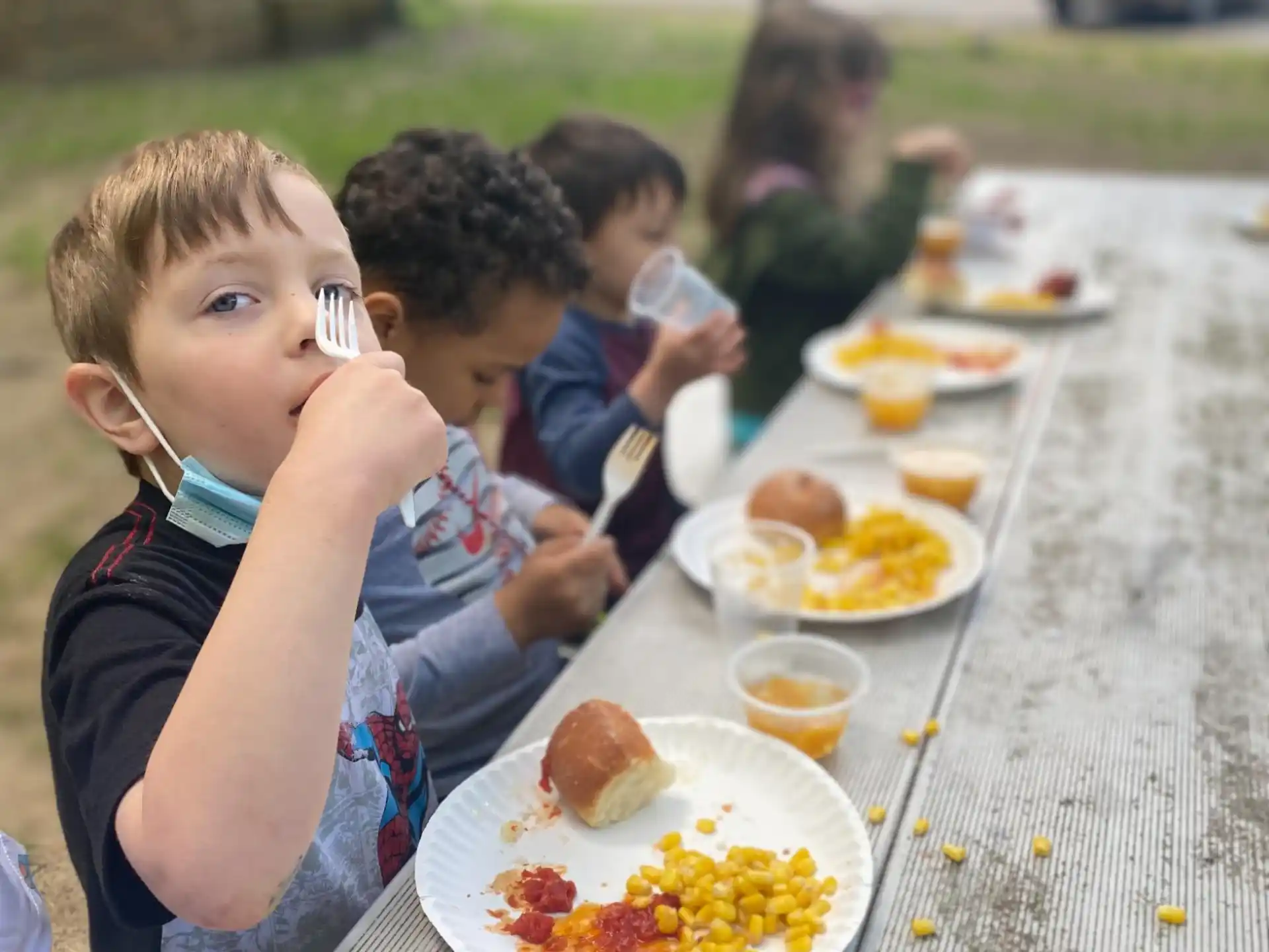 a group of kids eating at a picnic table