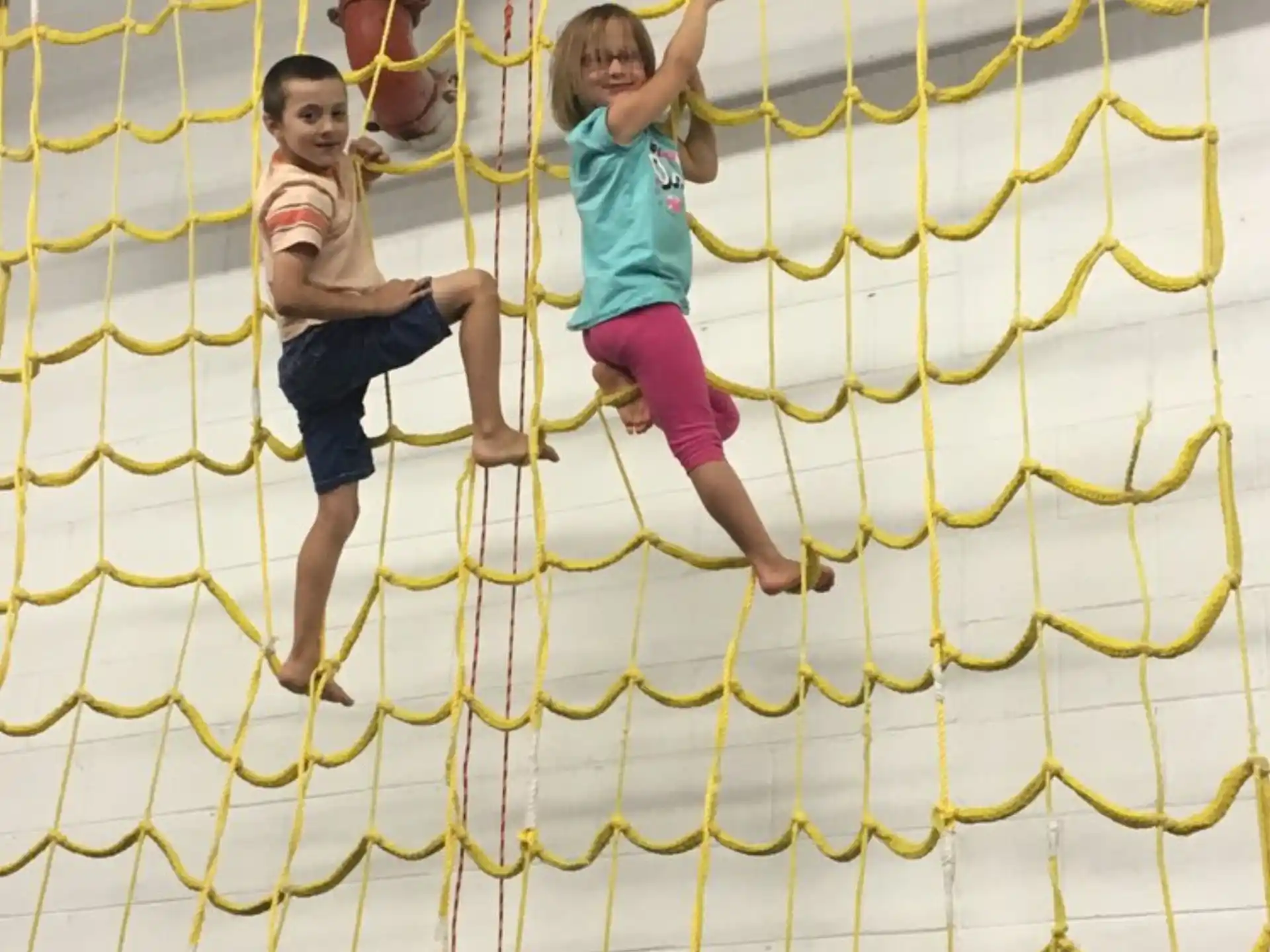 a couple of kids playing on a yellow and white trampoline