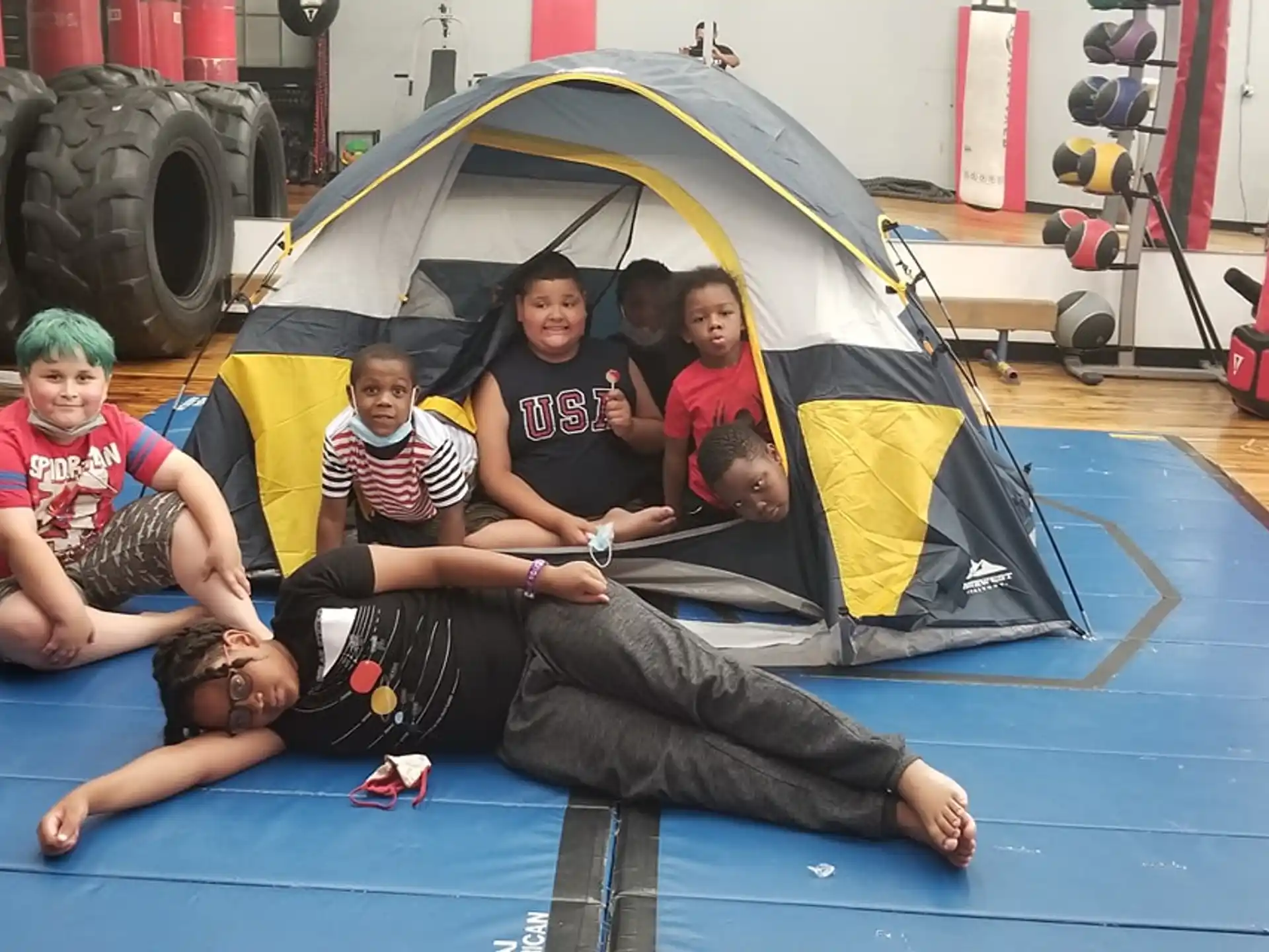 a group of people sitting on a mat in front of a car