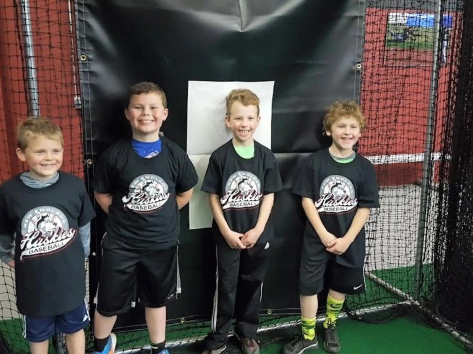 a group of boys in black t-shirts standing in front of a net