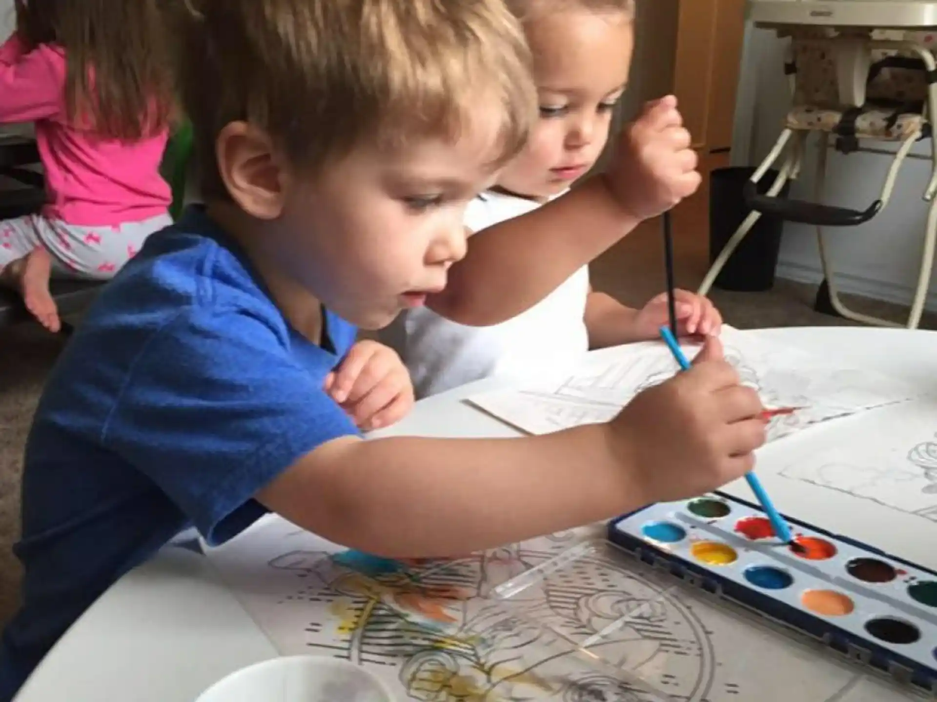 a few children coloring on a paper