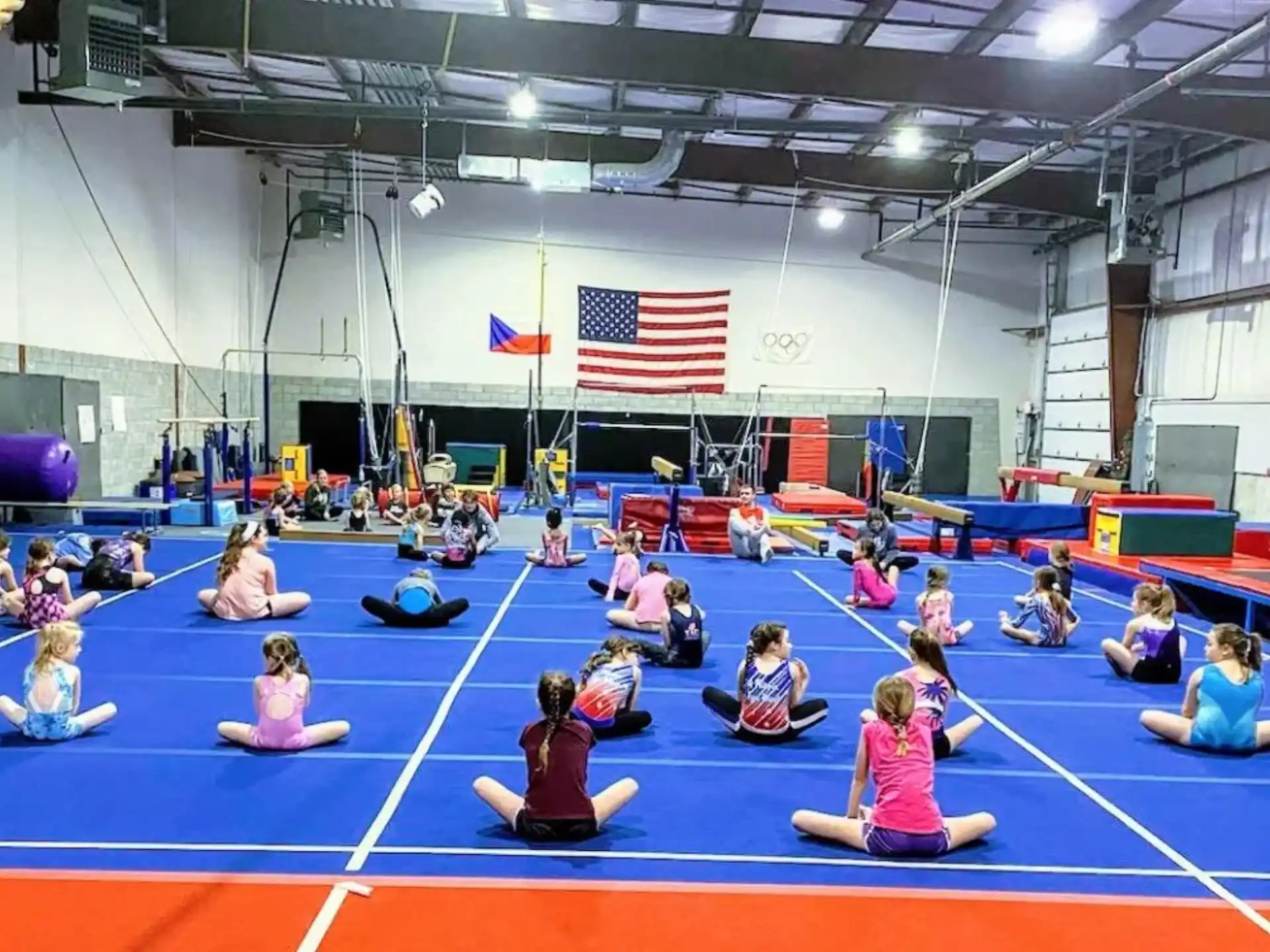 a group of people sitting on mats in a room with flags