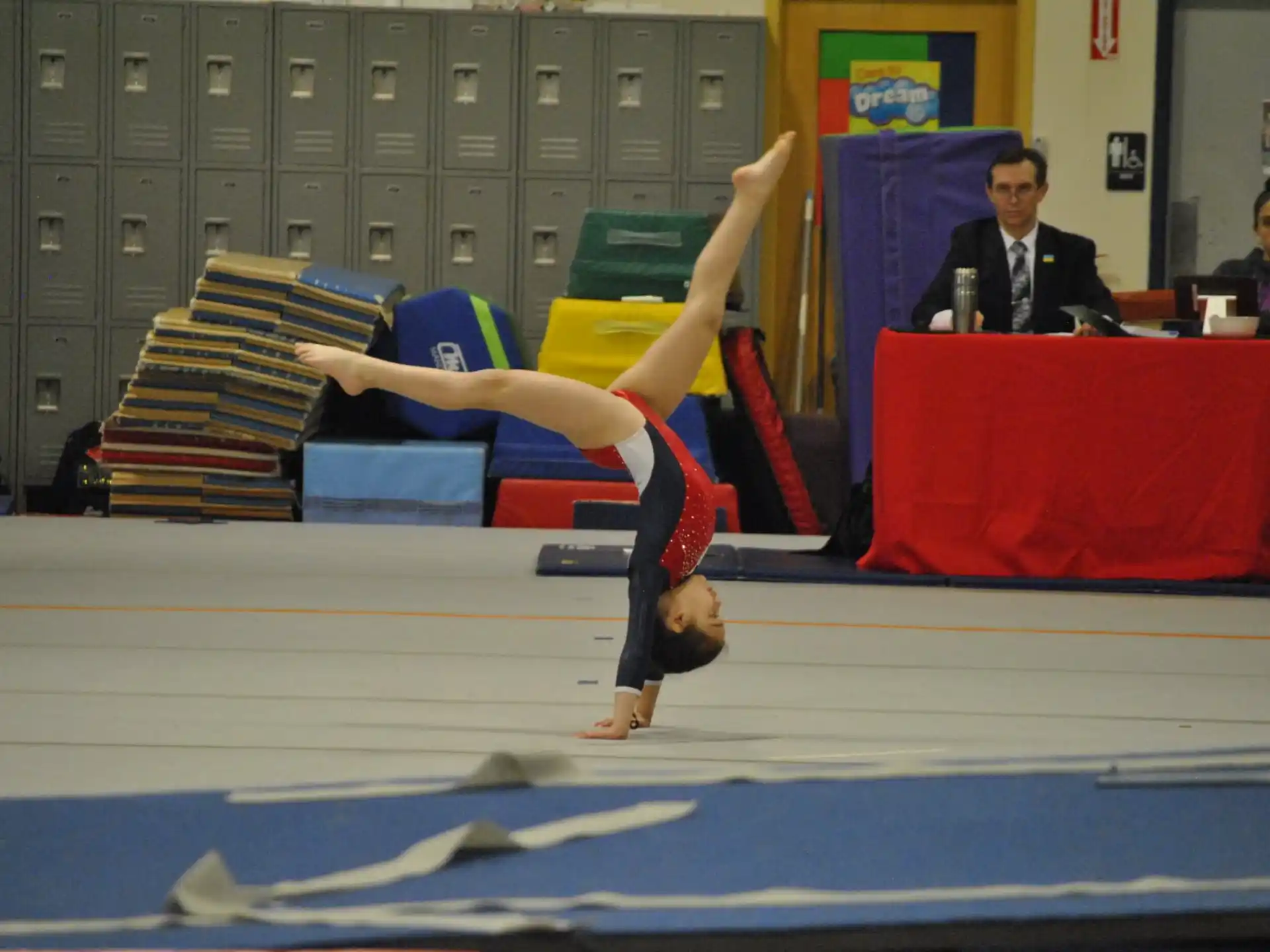 a person doing a handstand on a mat in front of a group of people