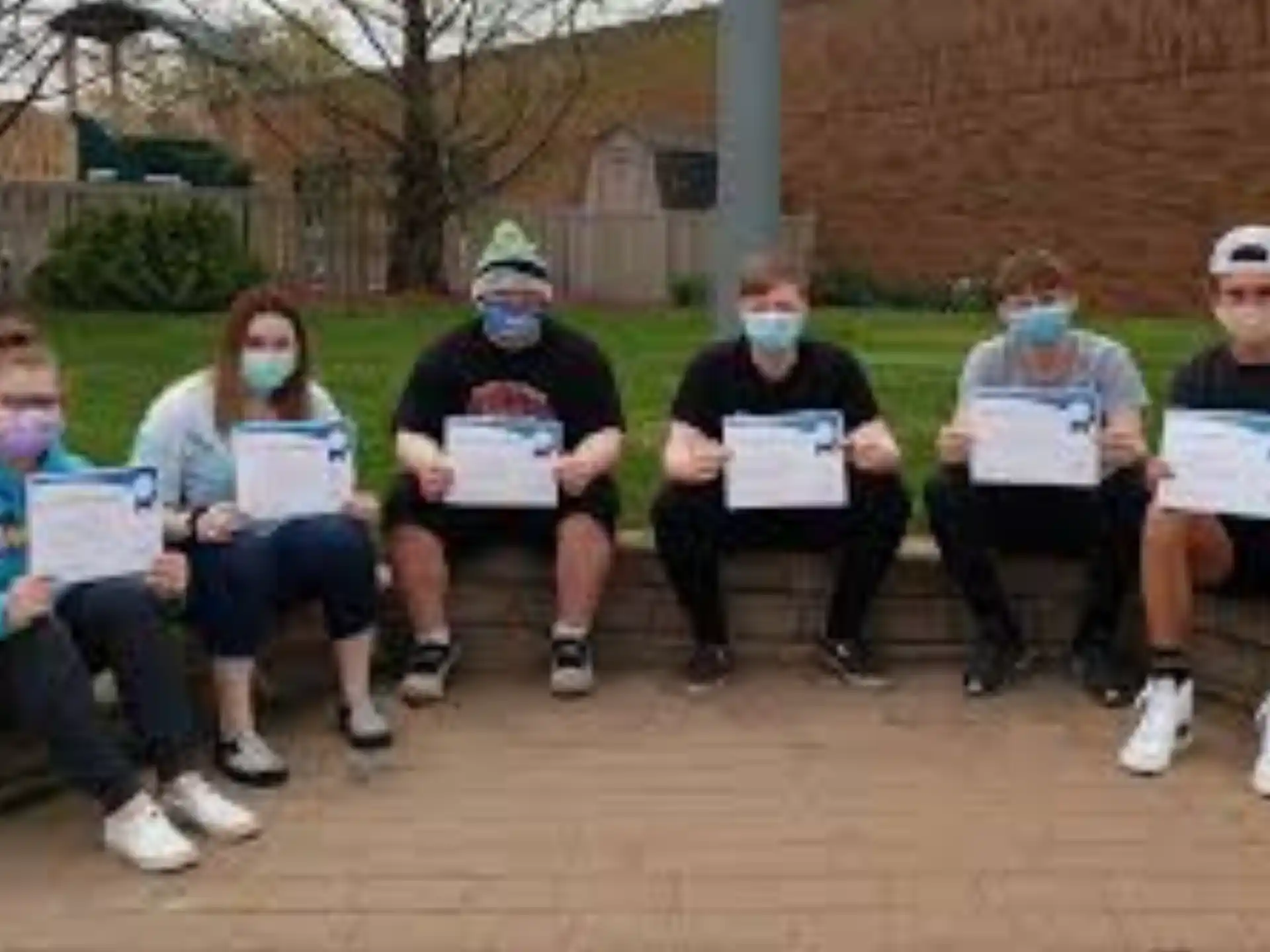 a group of people sitting on a bench holding papers