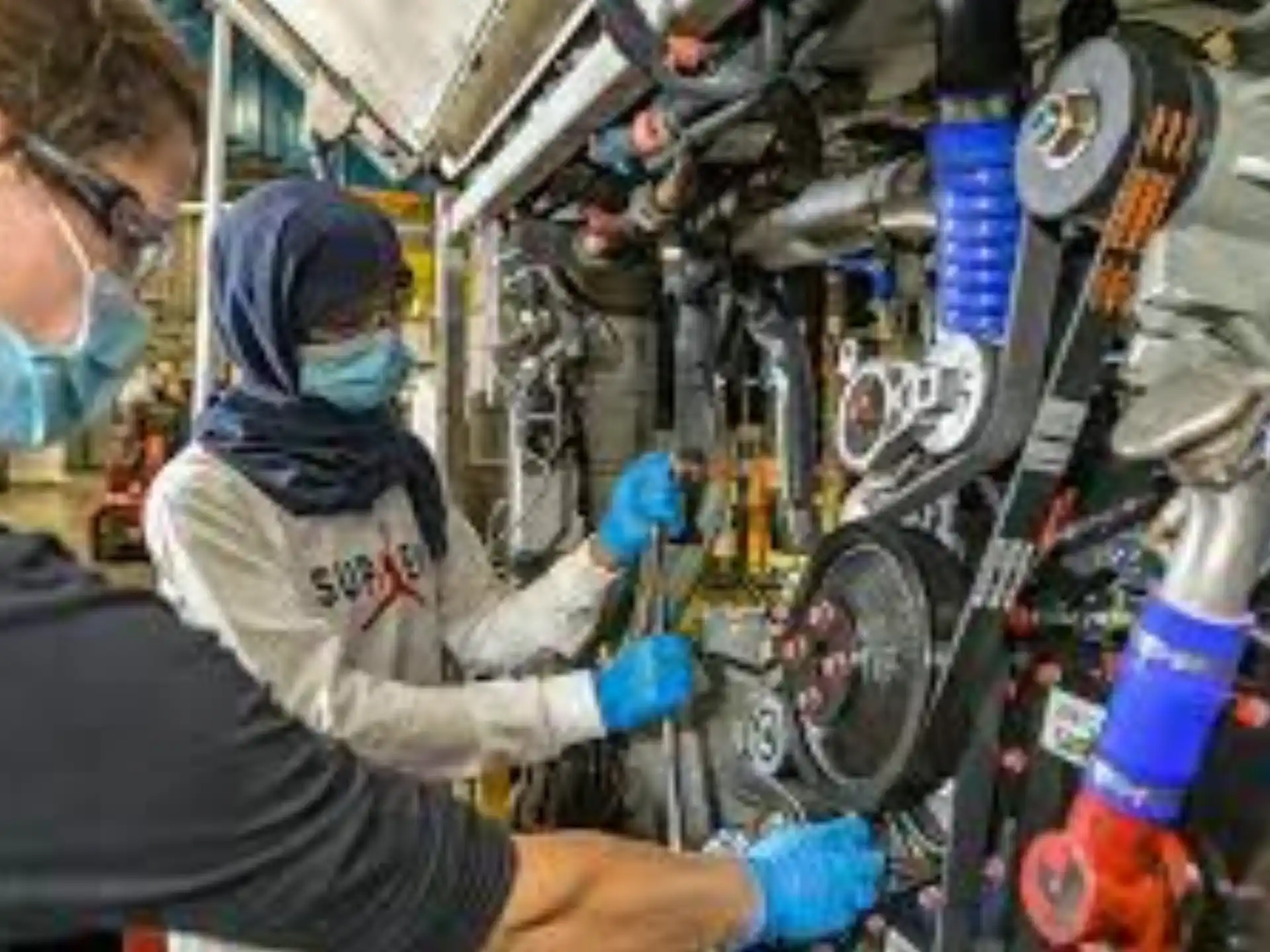 a man and a woman working on a car engine