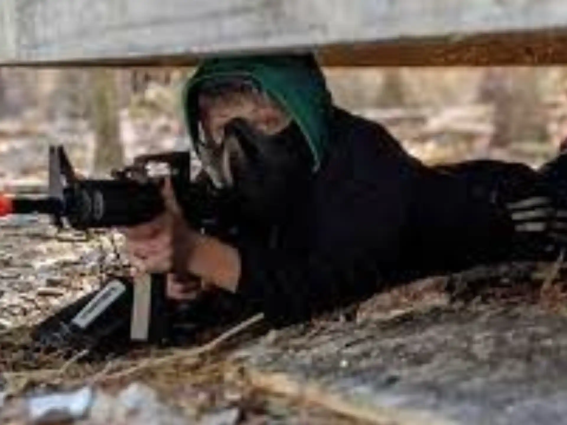 a person lying on the ground with a gun