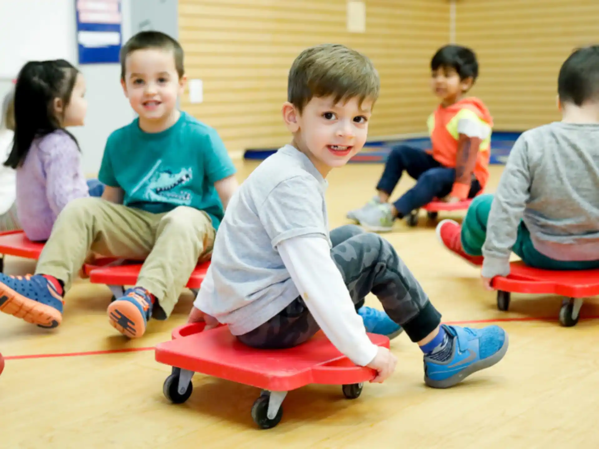a group of children sitting on red toy skateboards