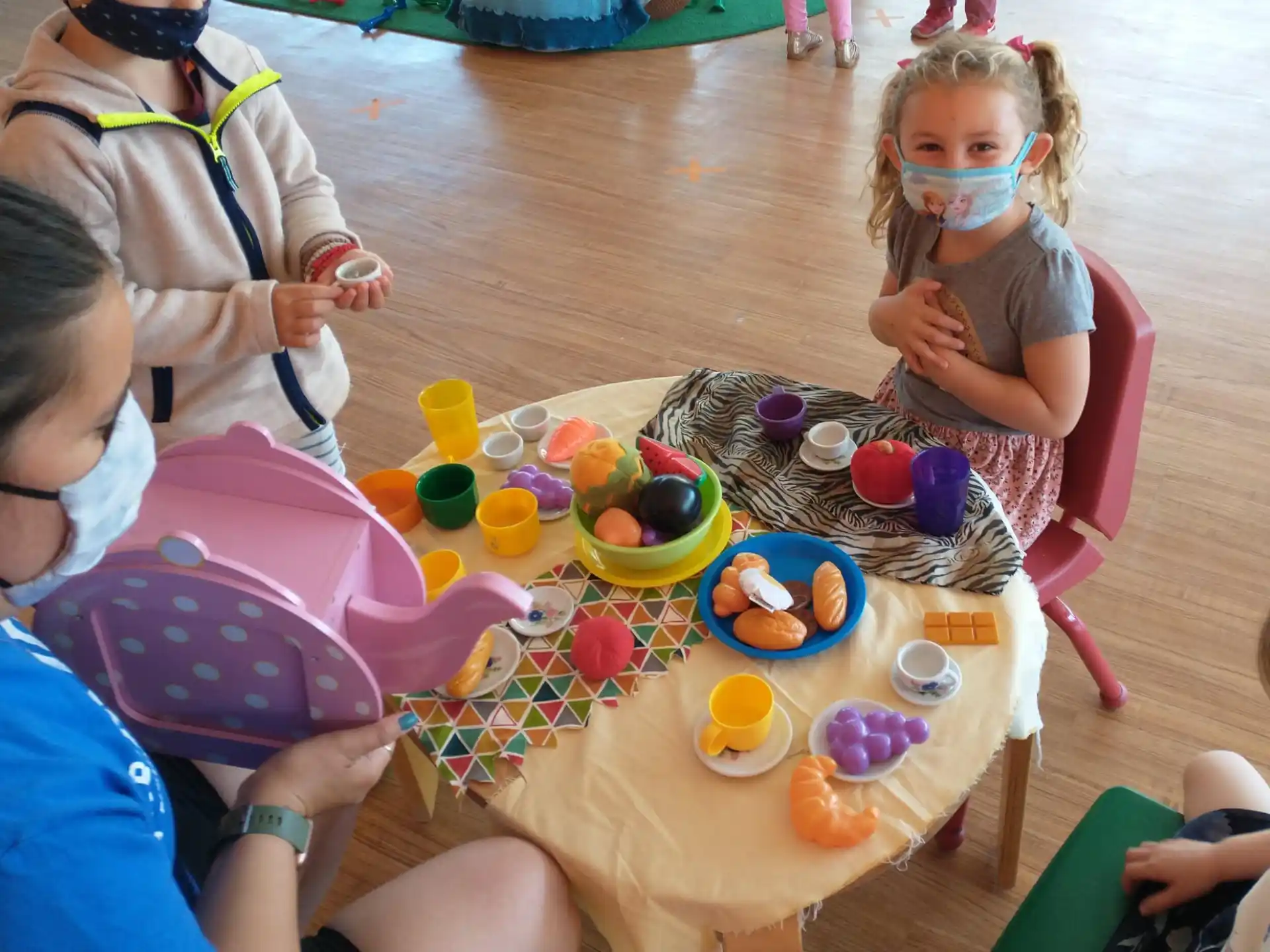 a group of children sitting around a table with food on it