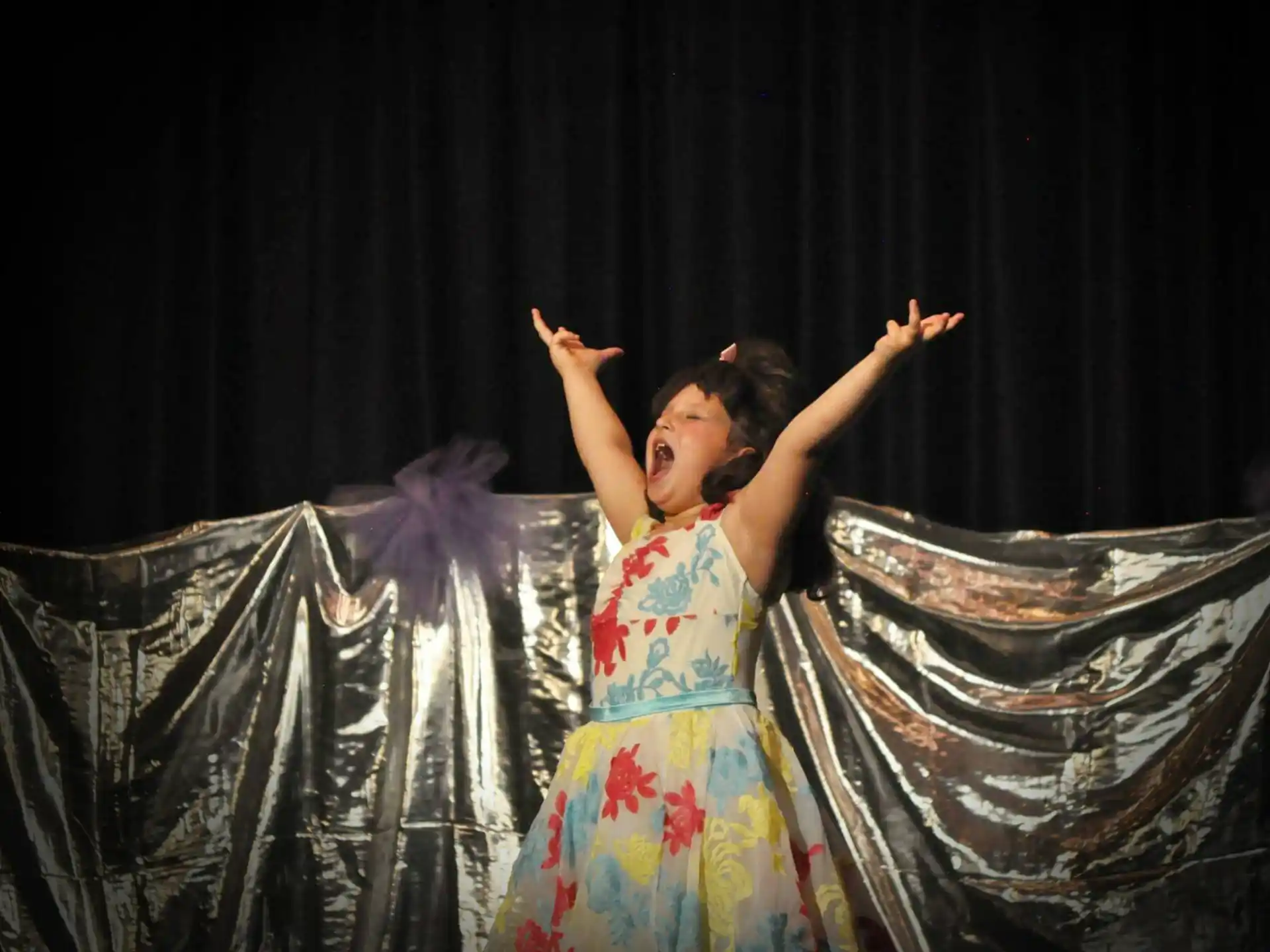 a woman in a dress with her arms raised in the air