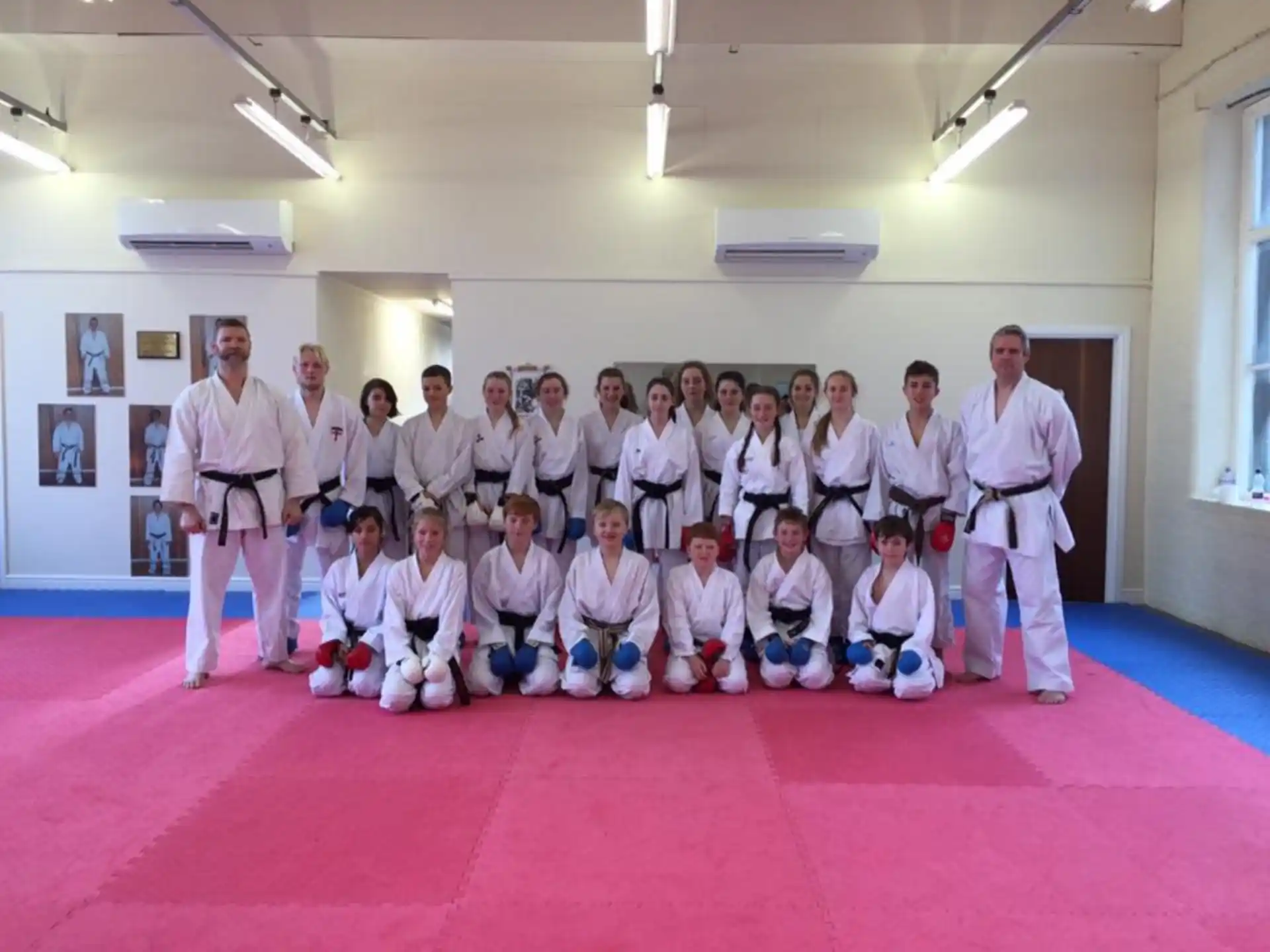 a group of people in white karate uniforms posing for a photo