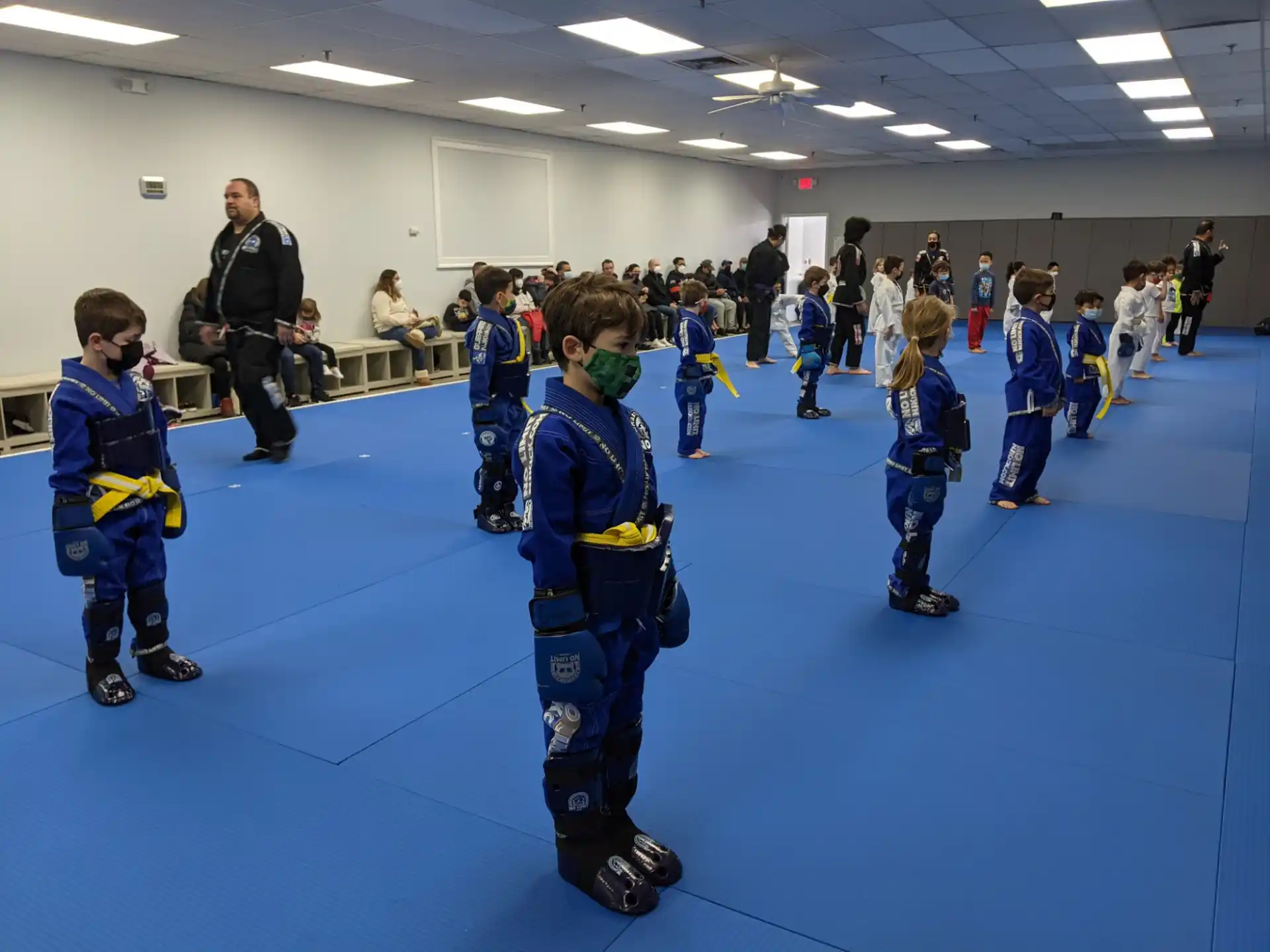 a group of kids wearing ice skates and standing on a blue mat
