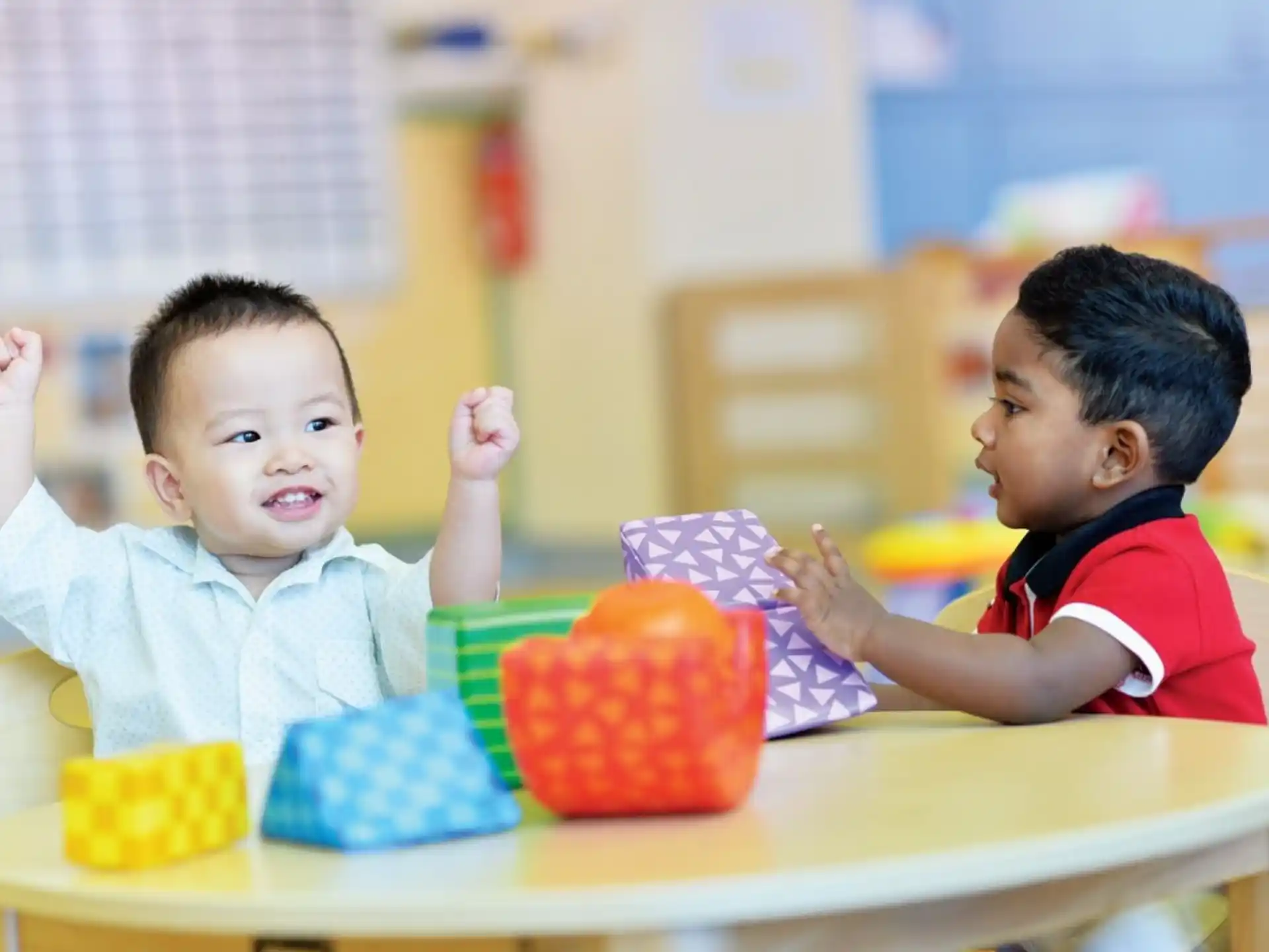 a couple of kids sitting at a table with a cake