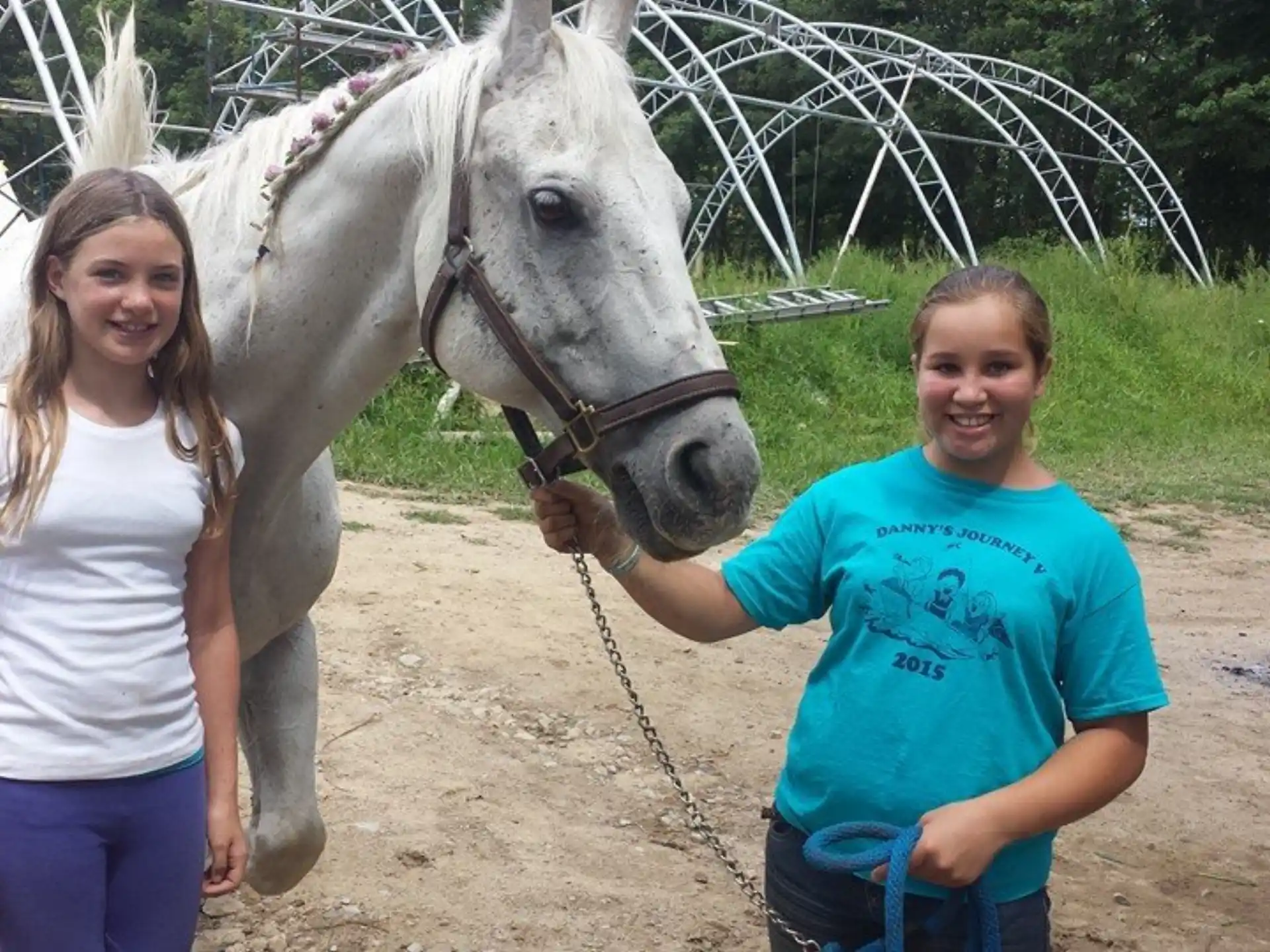 a couple of girls standing next to a horse